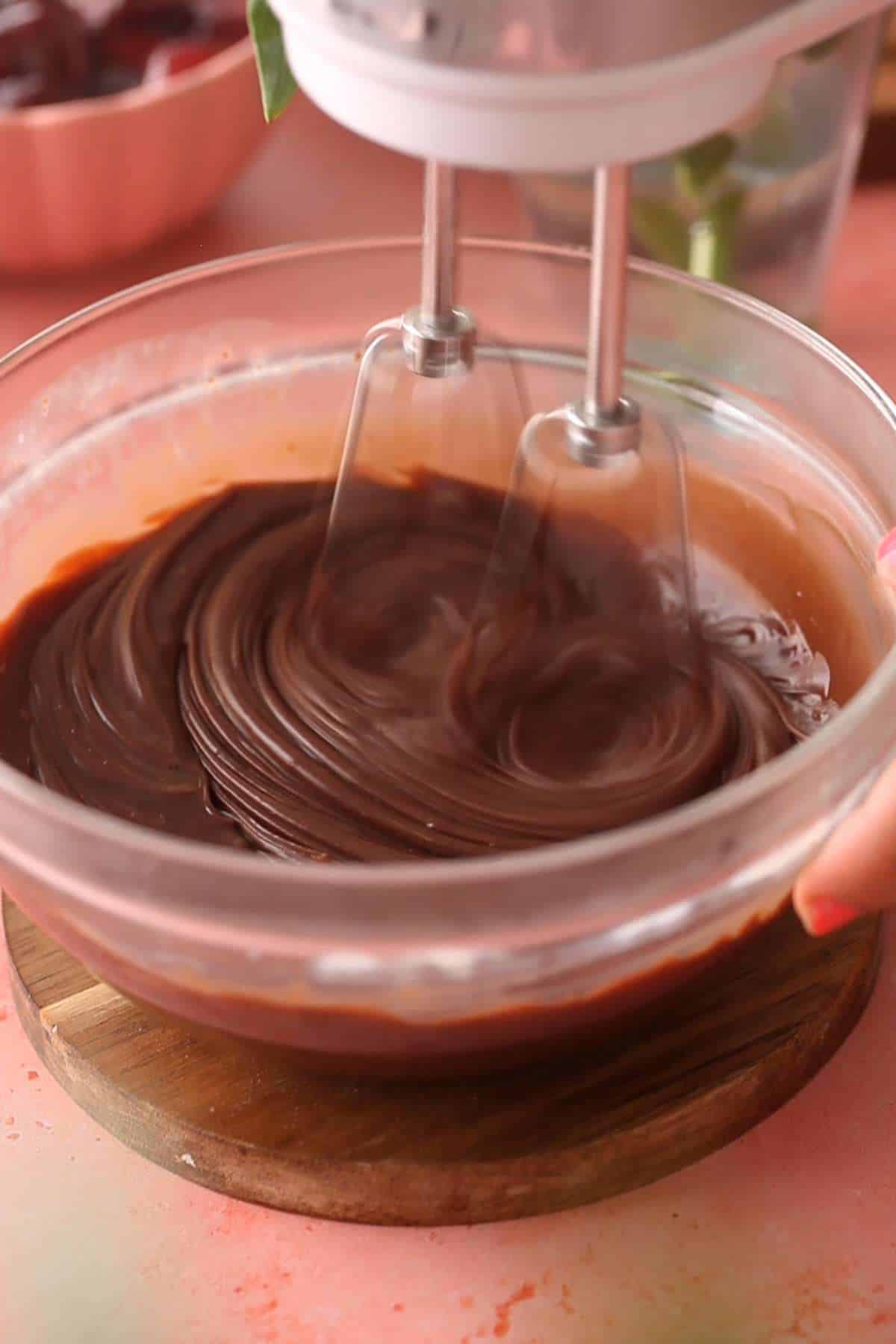 Whisking chocolate and cream mixture to make a chocolate pudding.