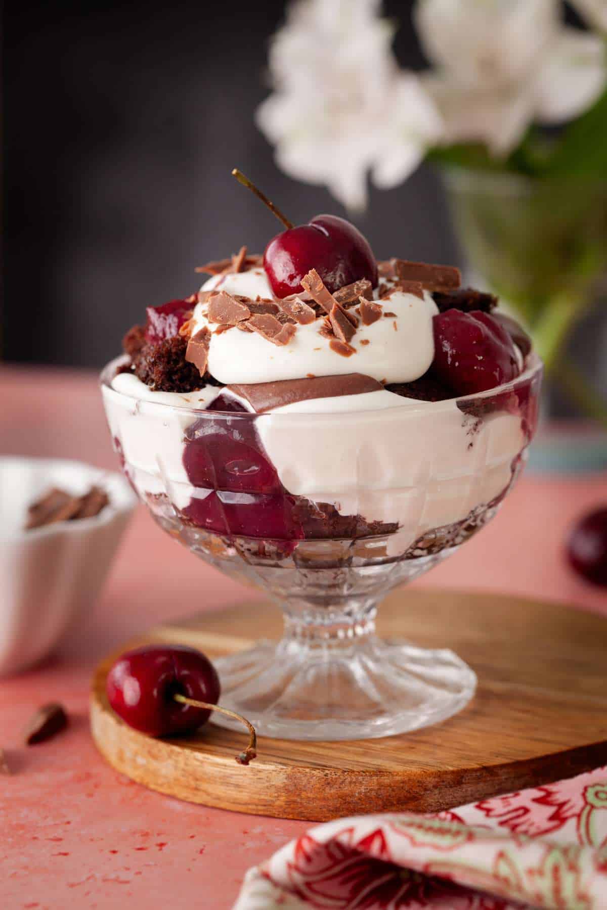 Black forest trifle in a glass bowl on a pink background.