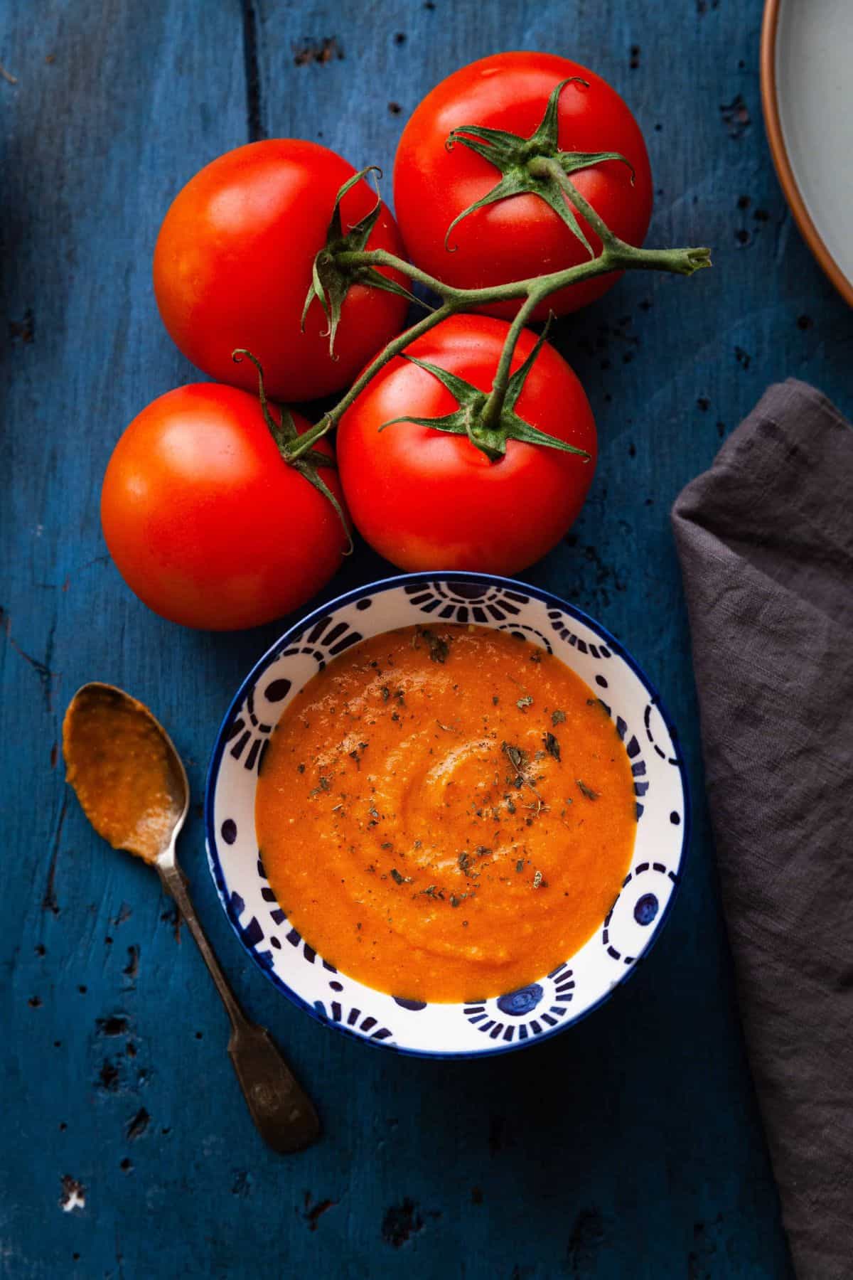 Makhani sauce in a blue bowl with tomatoes on vine.