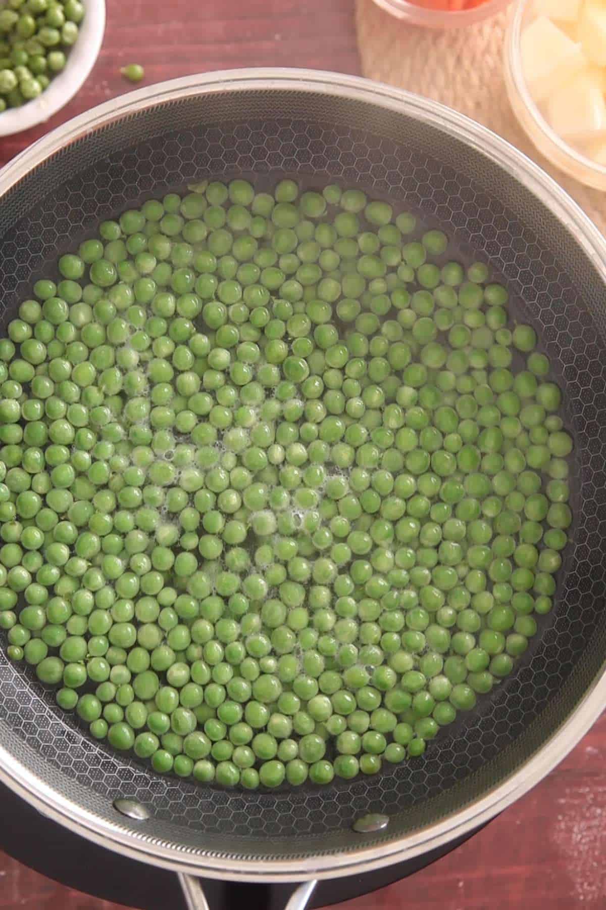 Blanching green peas in hot water.