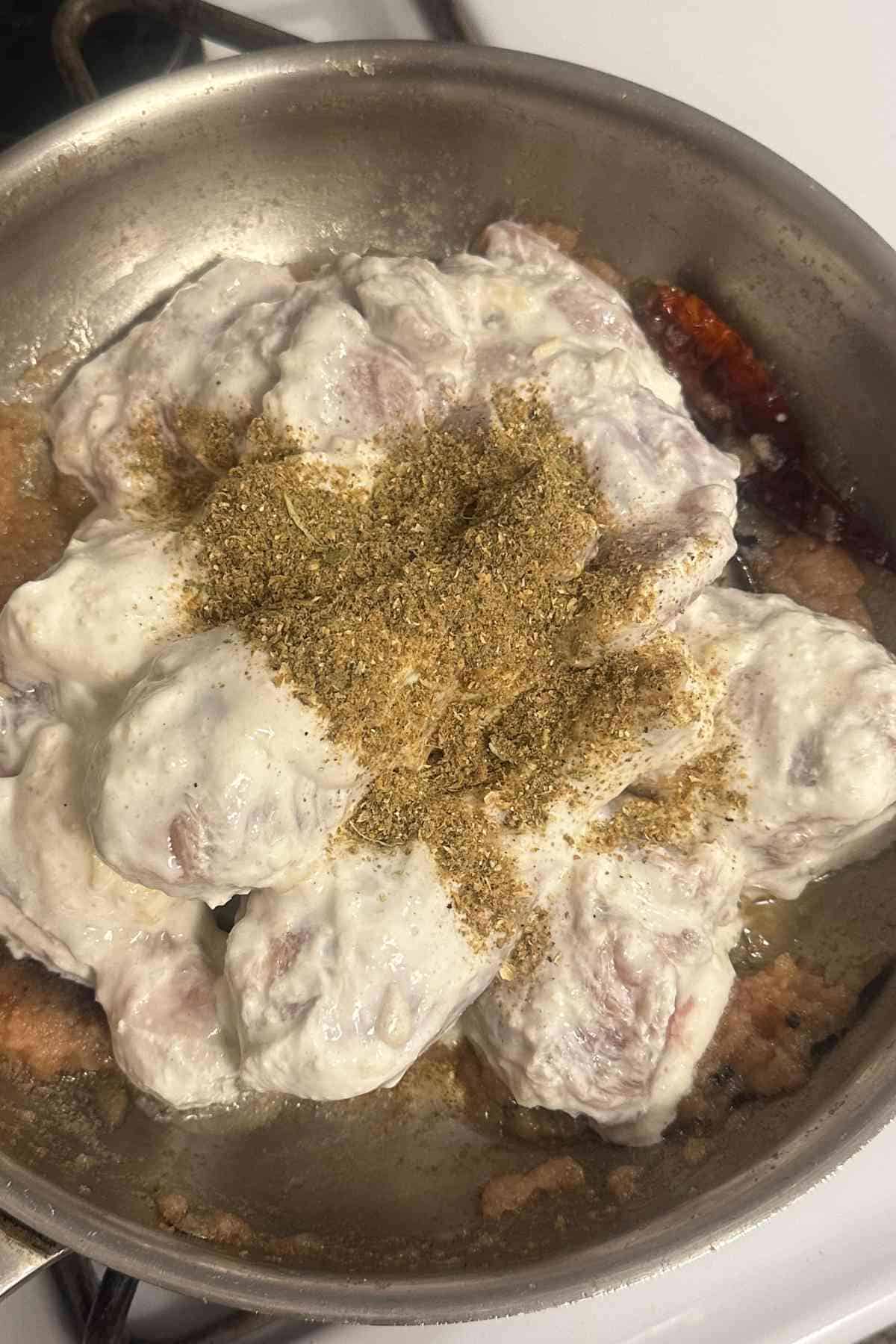 Adding marinated chicken and ground spices to the onions. 