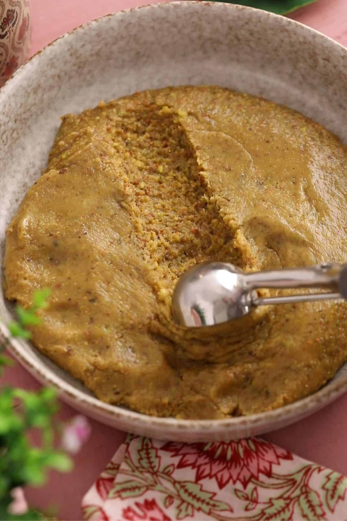 Scooping the ladoo mixture with an cookie scoop. 