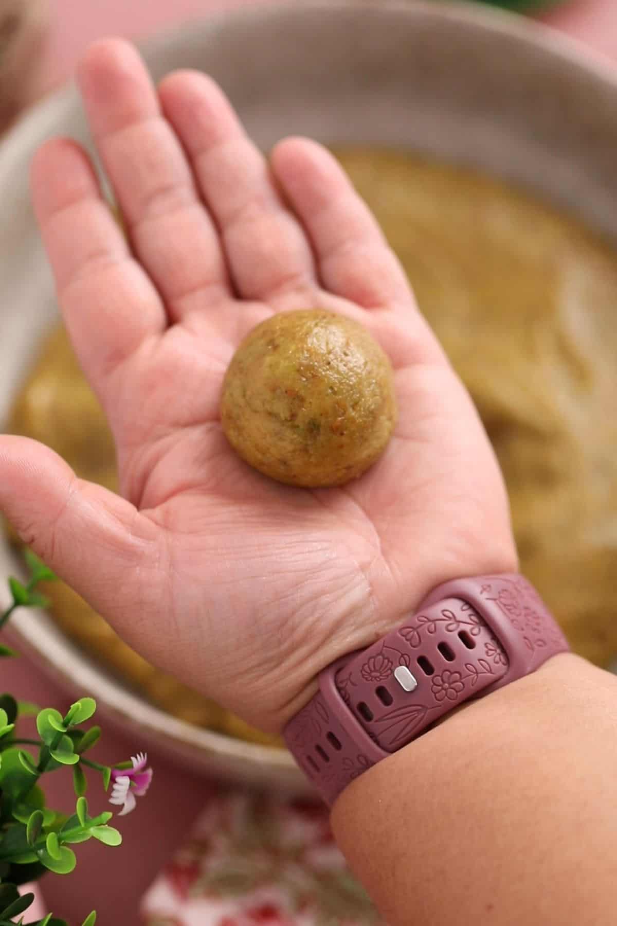 Rolled pistachio ladoo in hand.