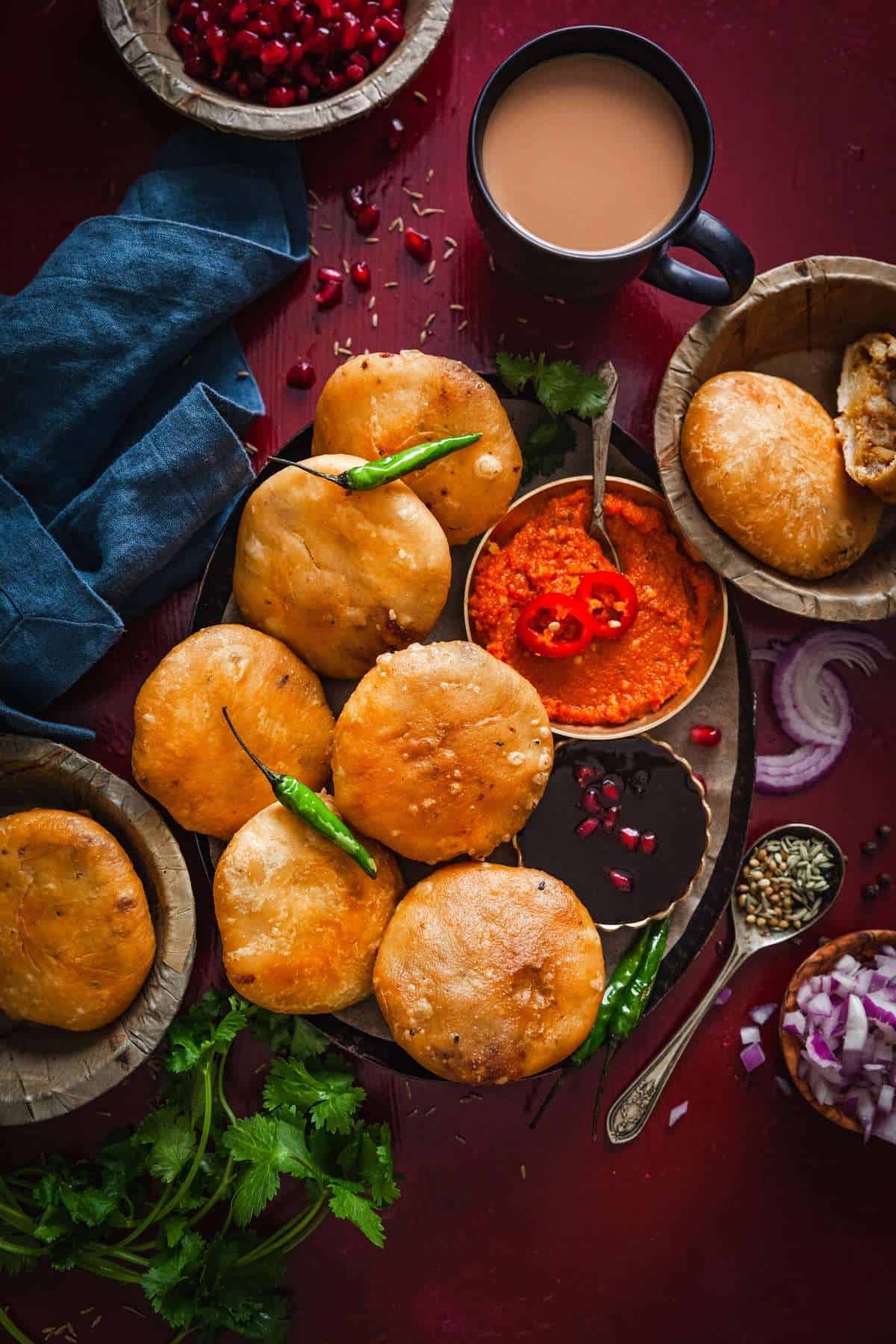 Pyaz ki kachoris on a palper with garlic chutney , green chillies and tamarind chutney