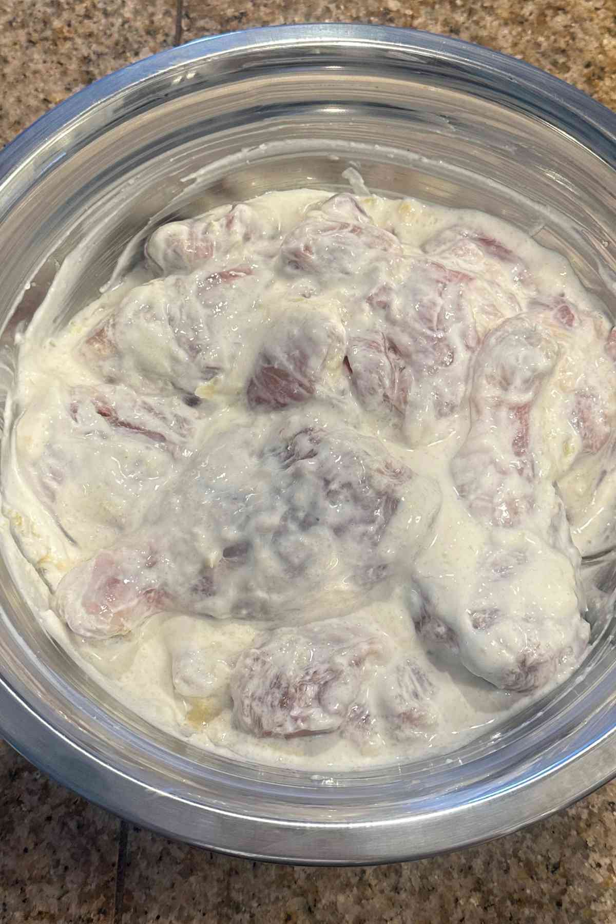 Marinated chicken in a steel bowl.