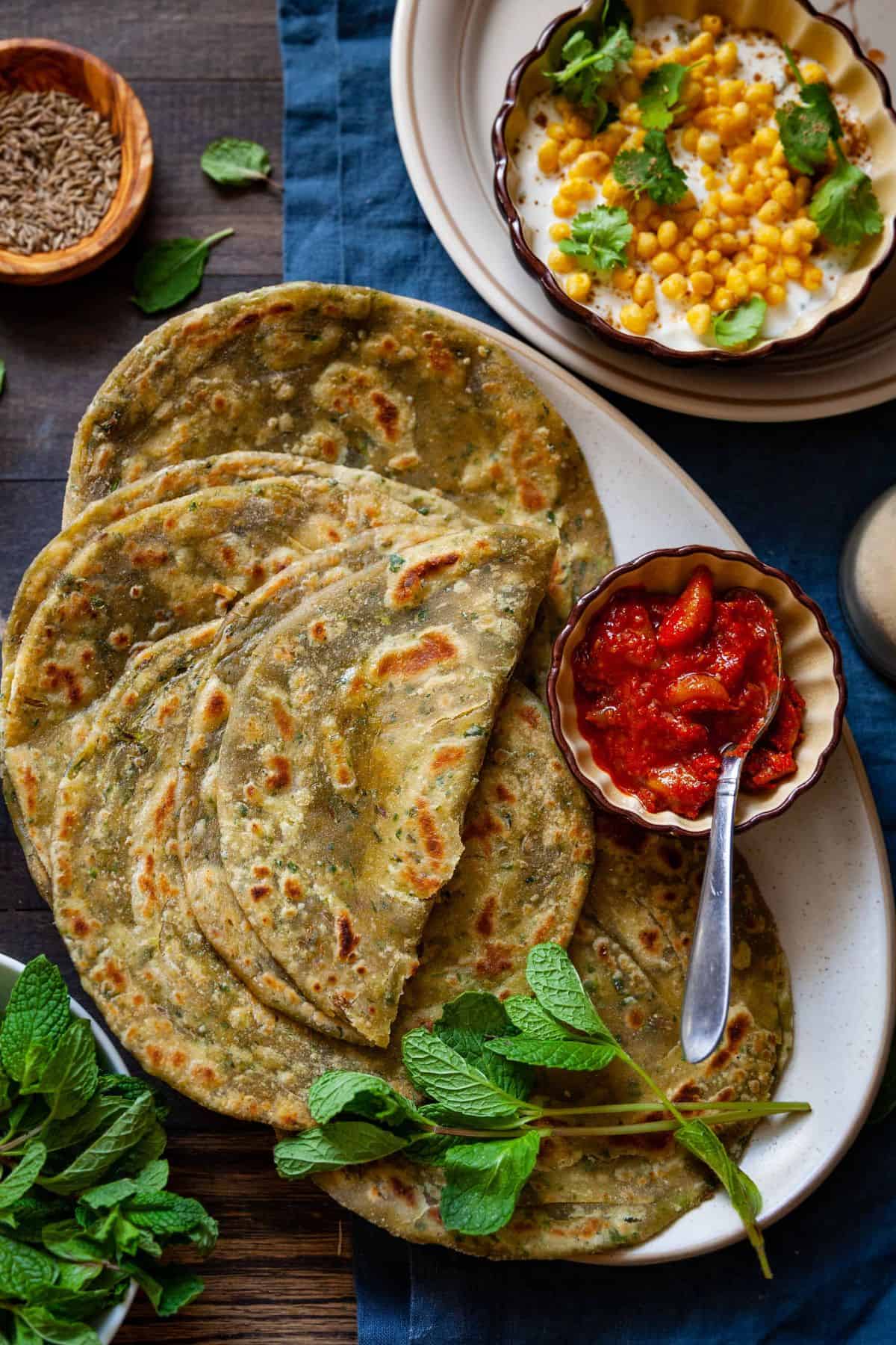 Close up shot of pudina parathas served with raita.