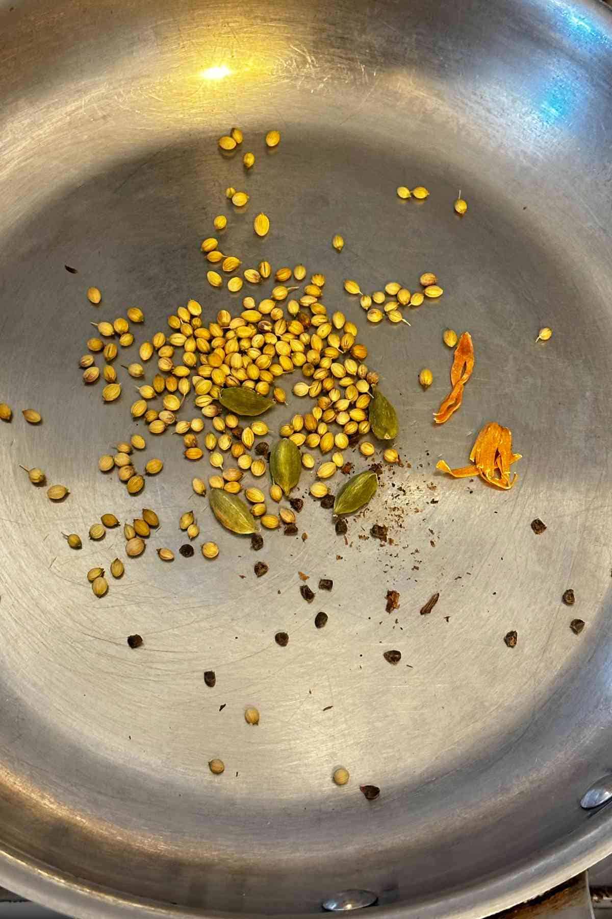 Toasting whole spices in a steel pan. 