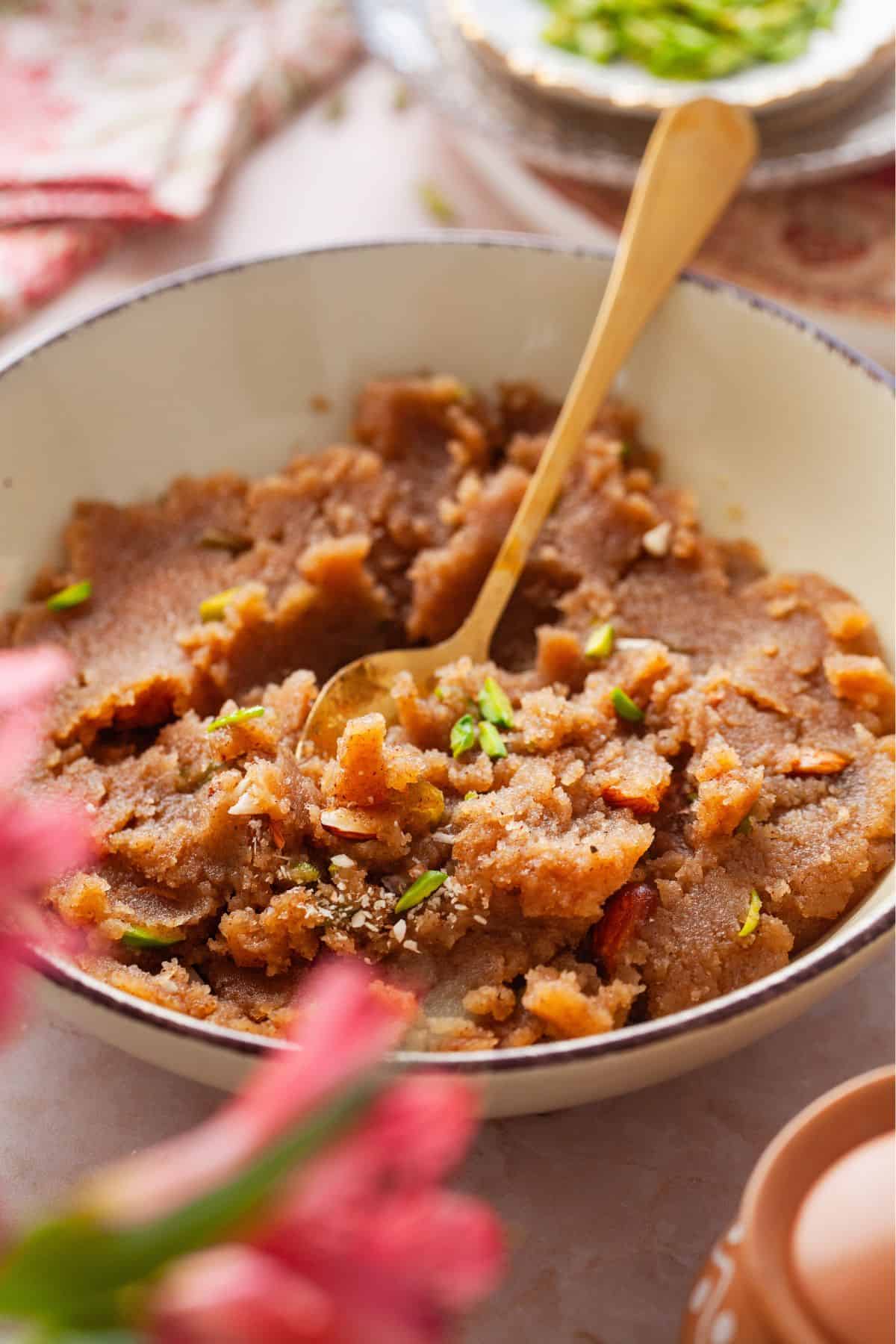 Sooji halwa is scooped with a gold spoon.