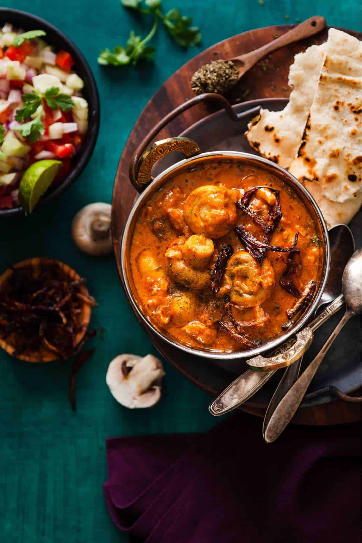 Mushroom Masala served in a stainless steel indian wok dish with rotis.