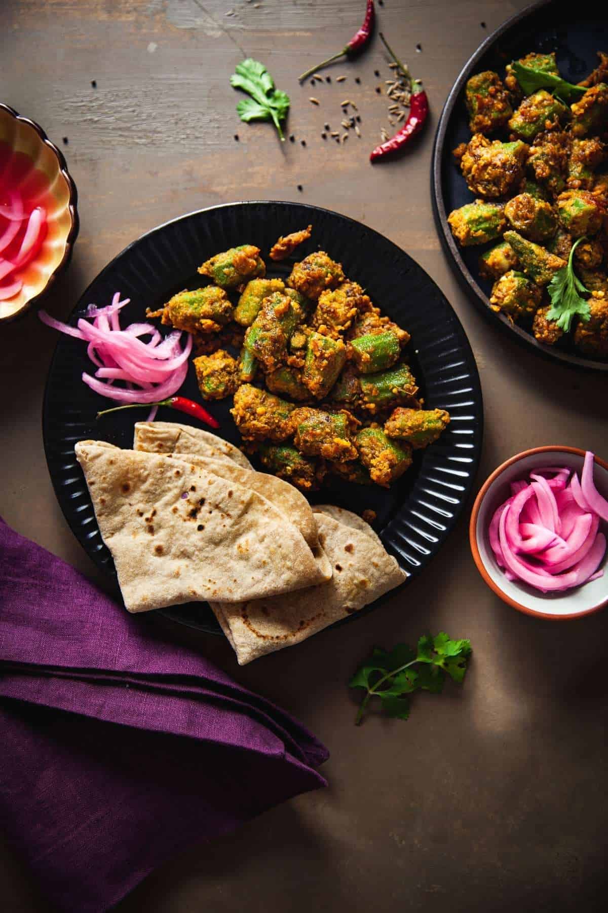 Besan Bhindi served with roti and pickled onions in plate.
