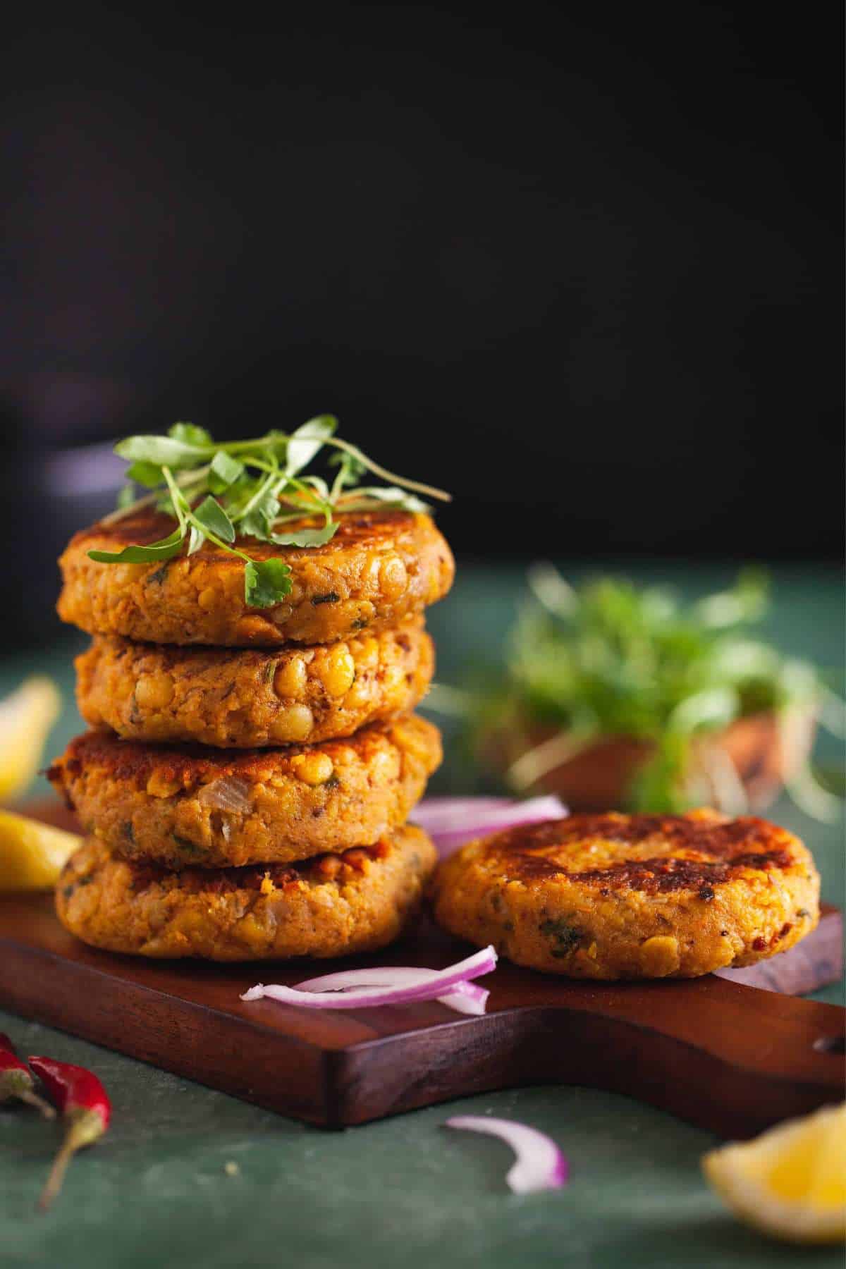 Lentil patties stacked on a wood board. 