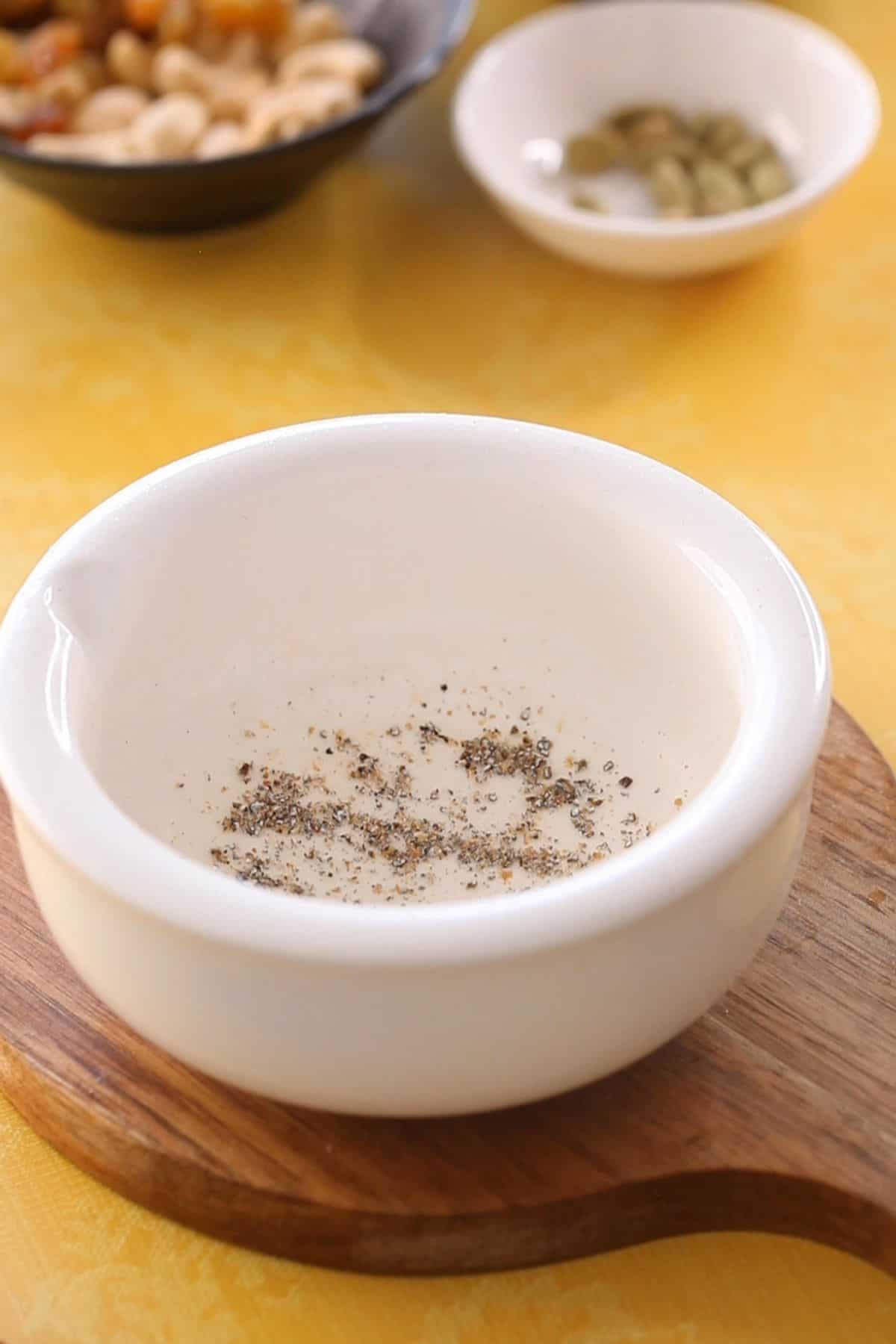 Fresh ground green cardamom powder in a white mortar.