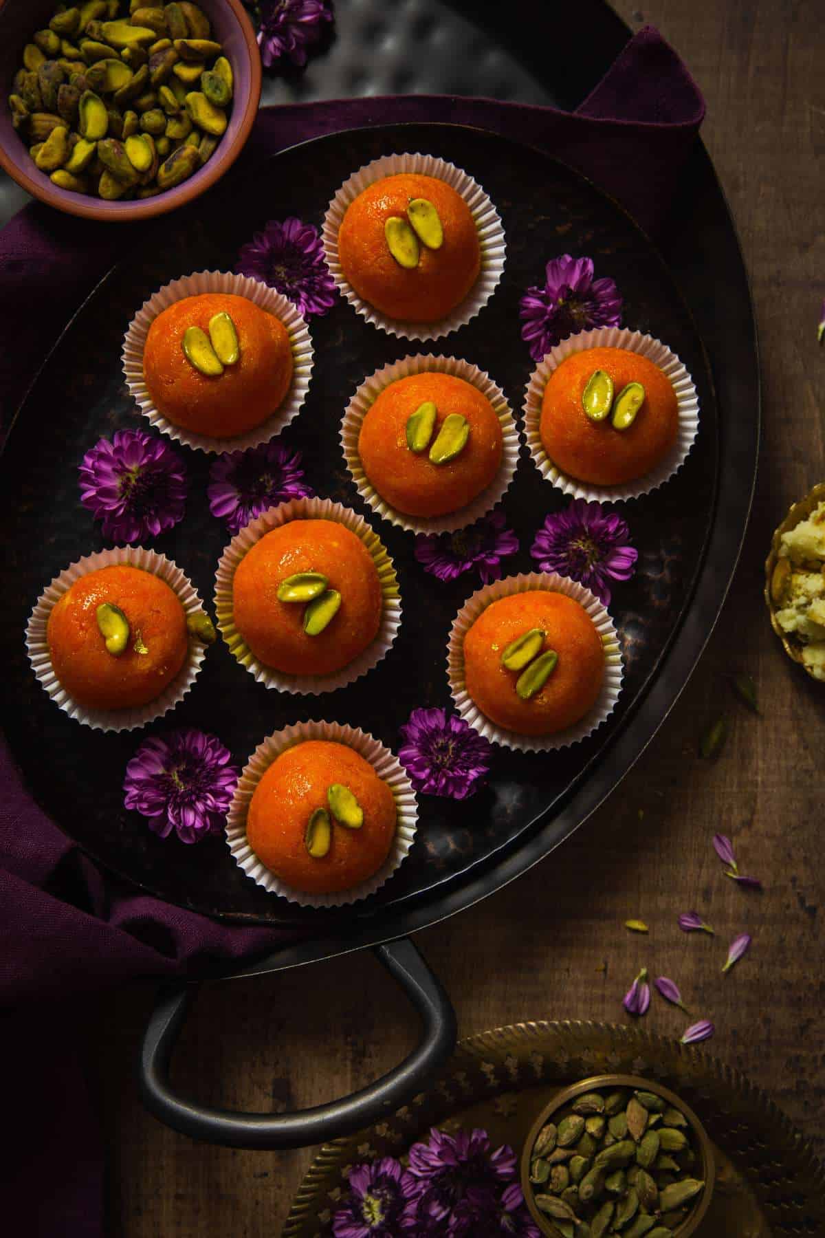 Gajar Ladoos on a black platter with purple flowers.