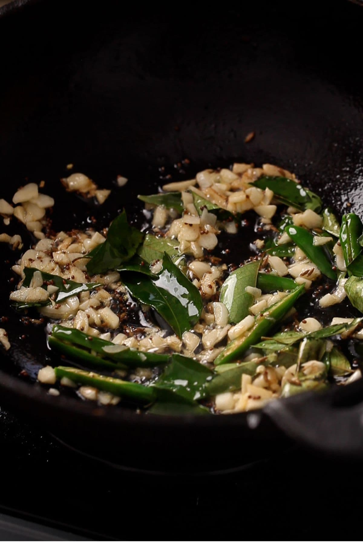 Garlic, green chilies and curry leaves in hot oil.
