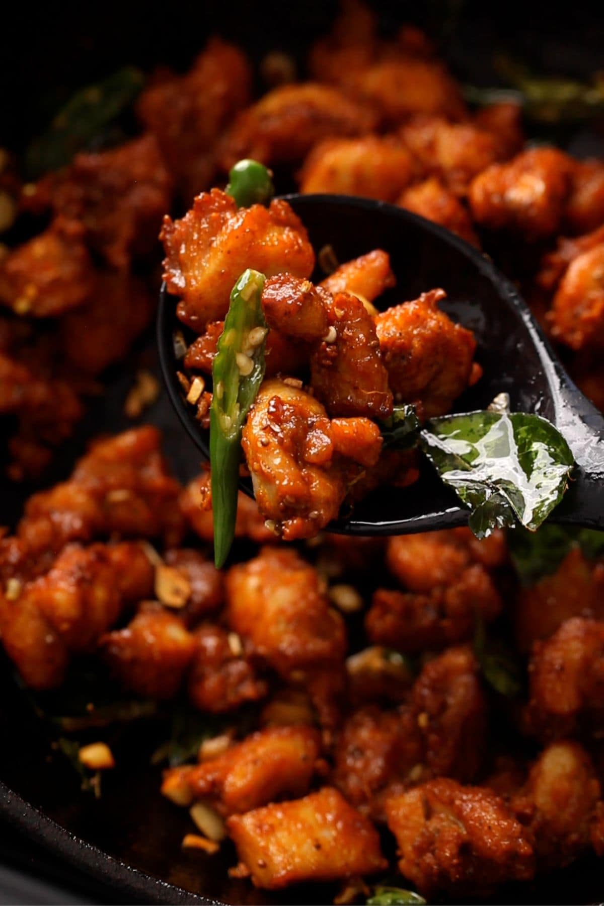 Close-up of spicy, fried chicken 65 pieces served on a black spoon.