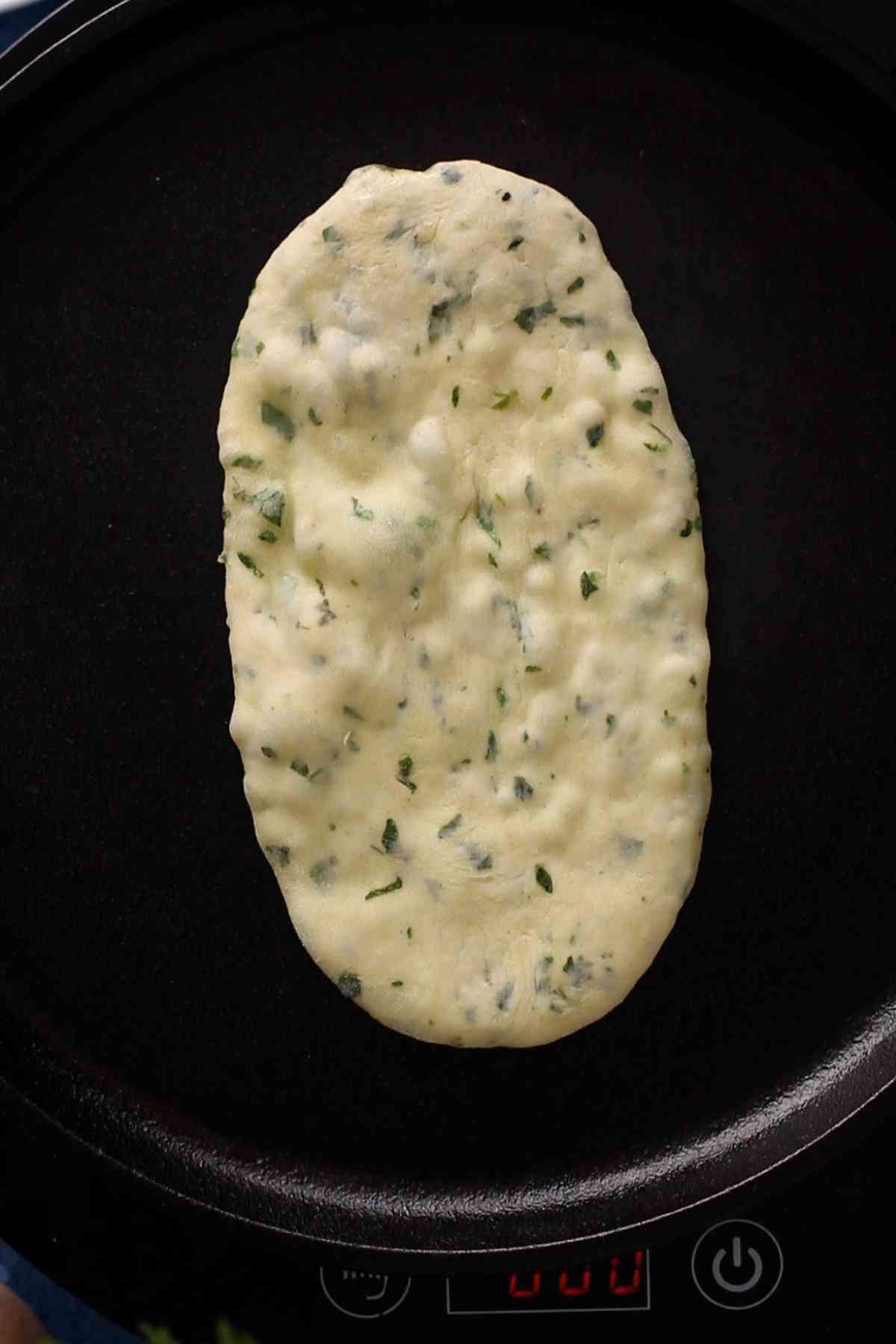 Puffed up naan on a cast iron griddle.
