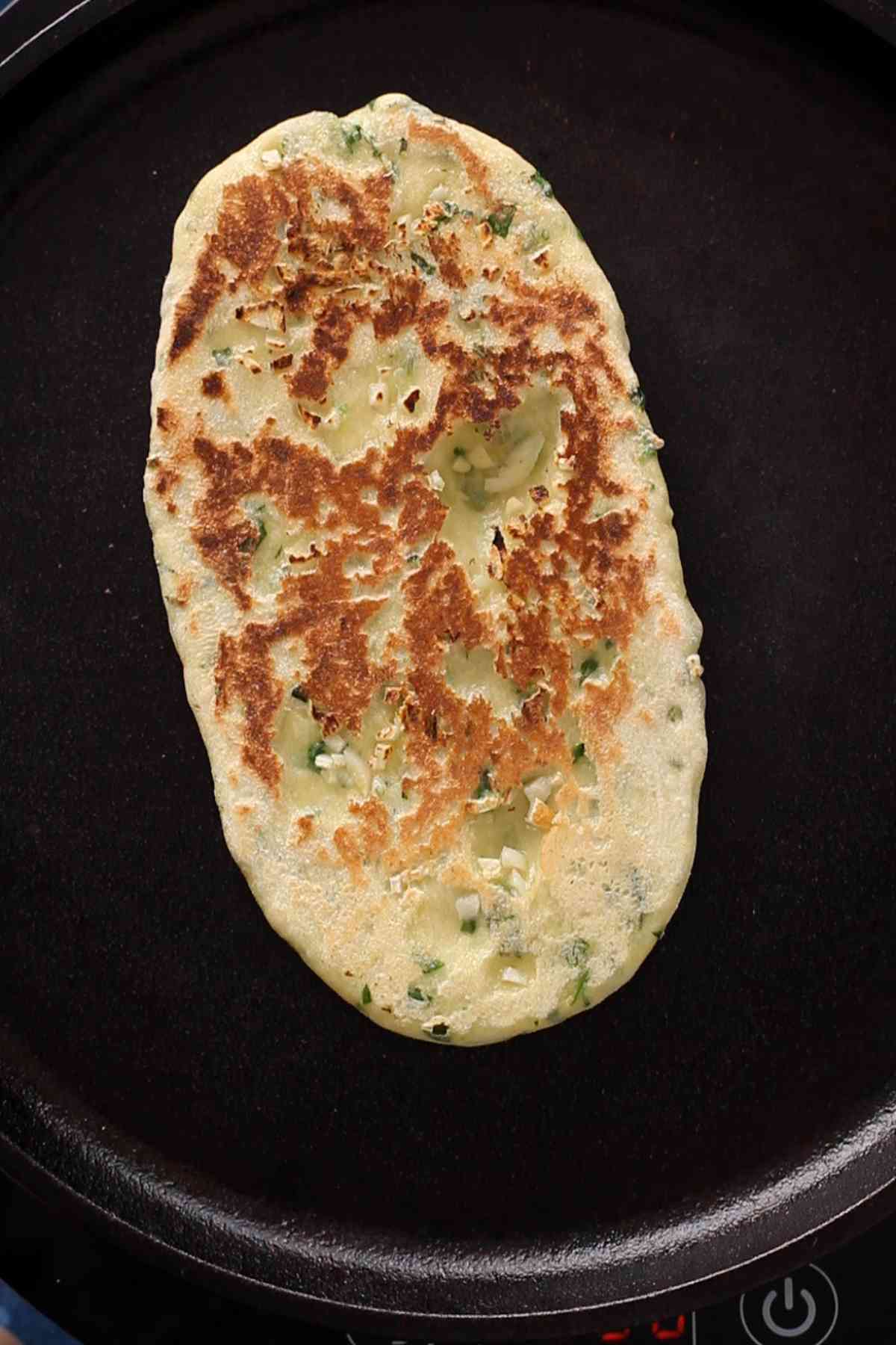 Cooked naan on the iron skillet.