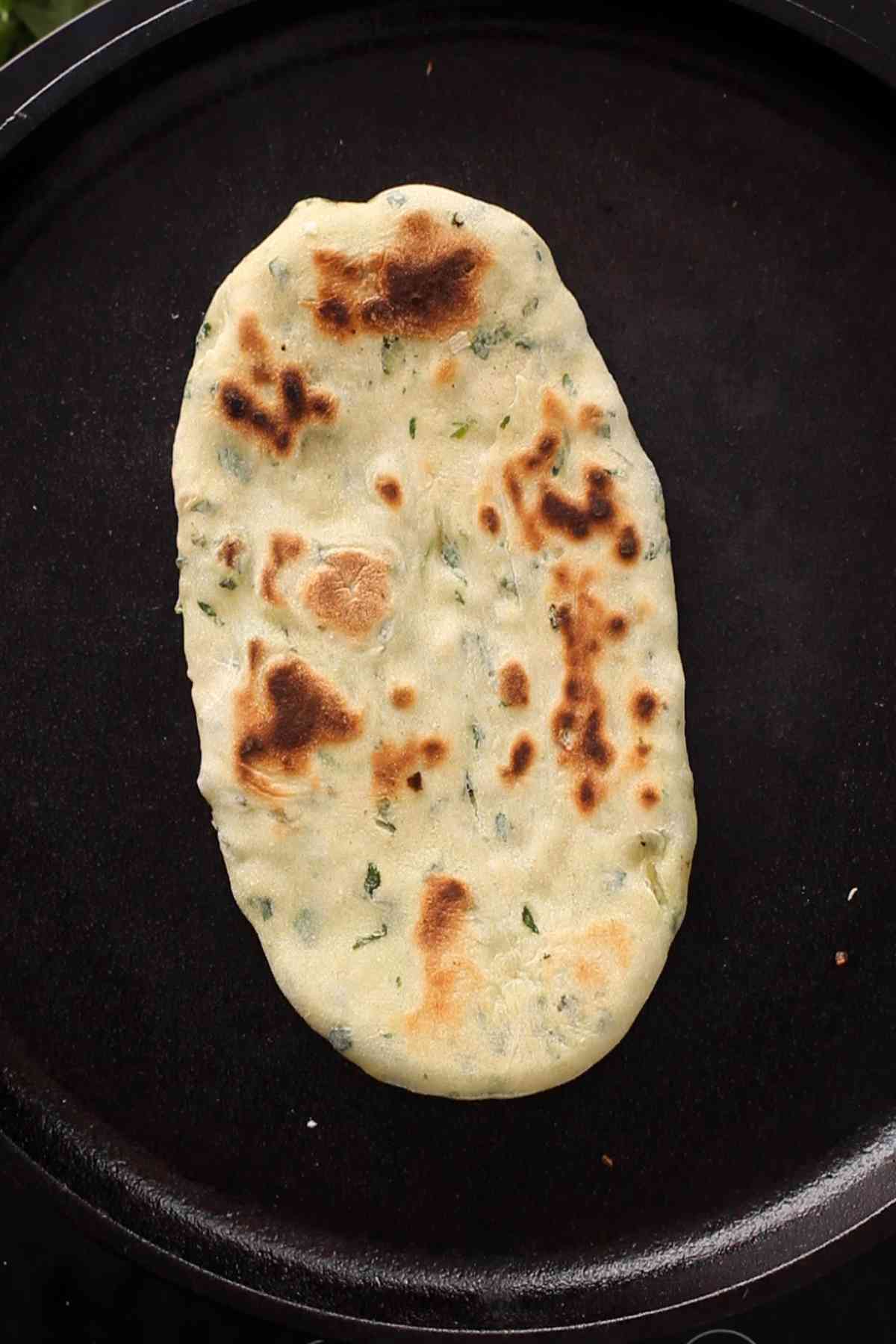 Charred spots on the naan after flipping.