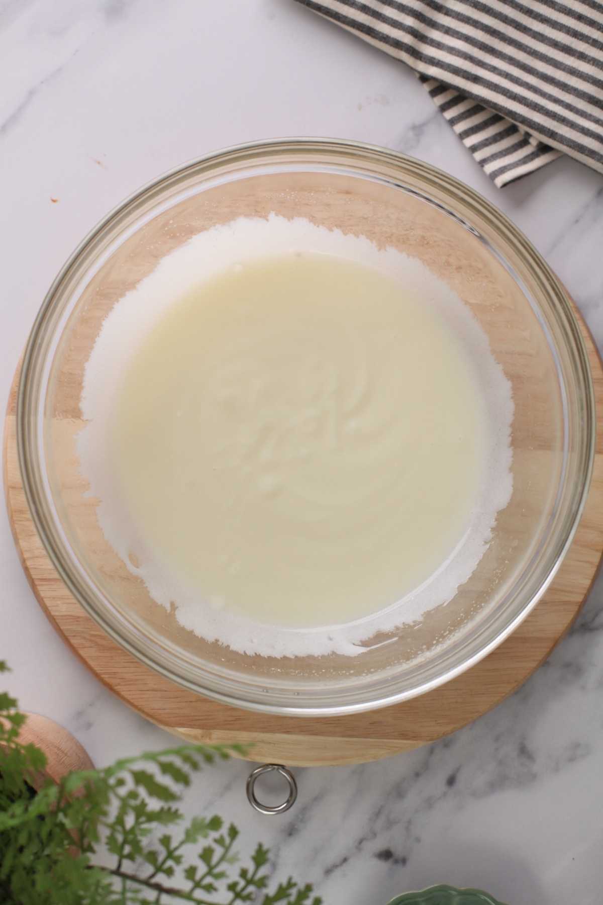 Wet ingredients combined together in a glass bowl for making eggless masala chai tres leches cake. 