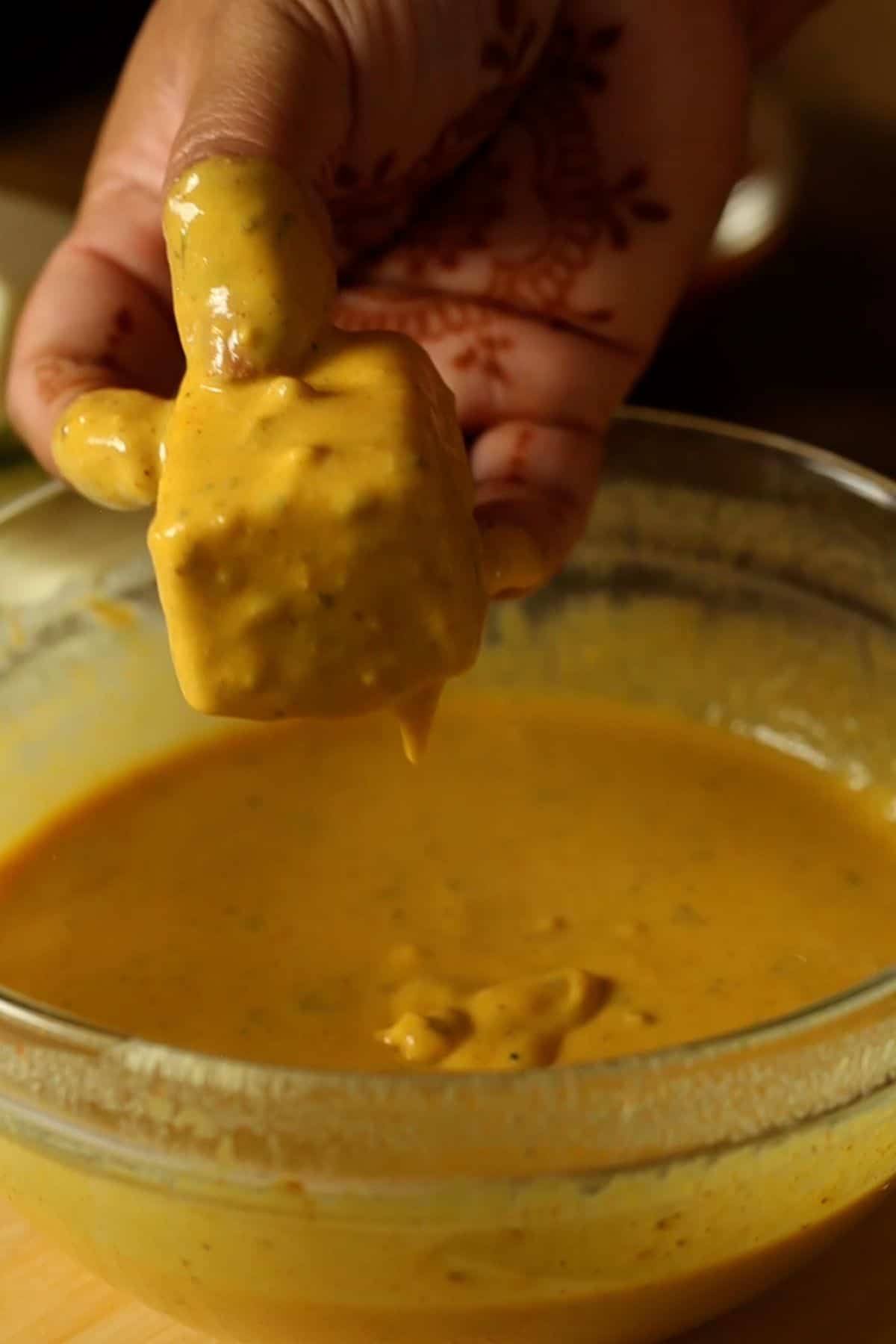 A paneer cube is coated in the pakora batter.