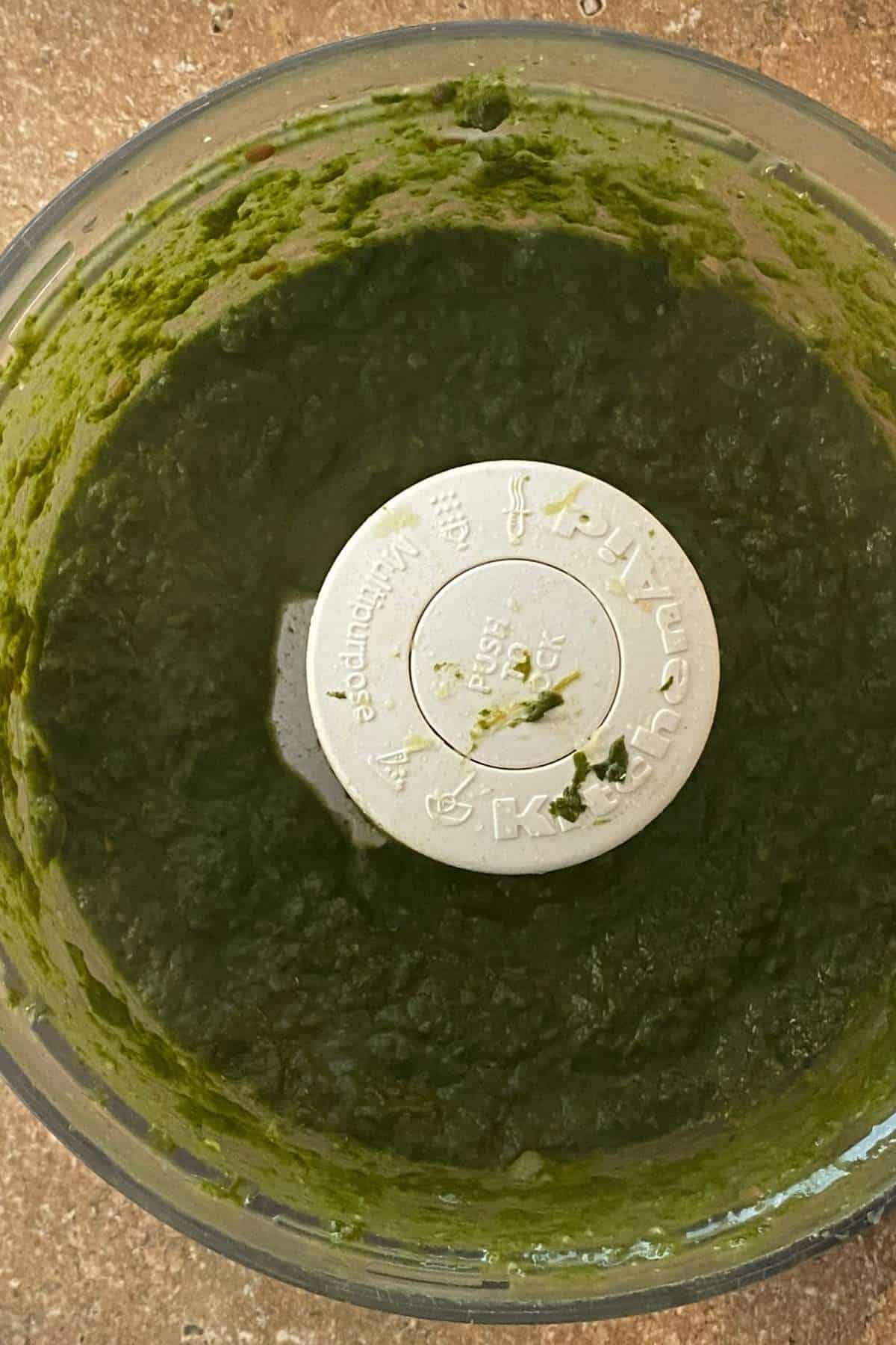 Add greens to a processor and make a coarse paste.