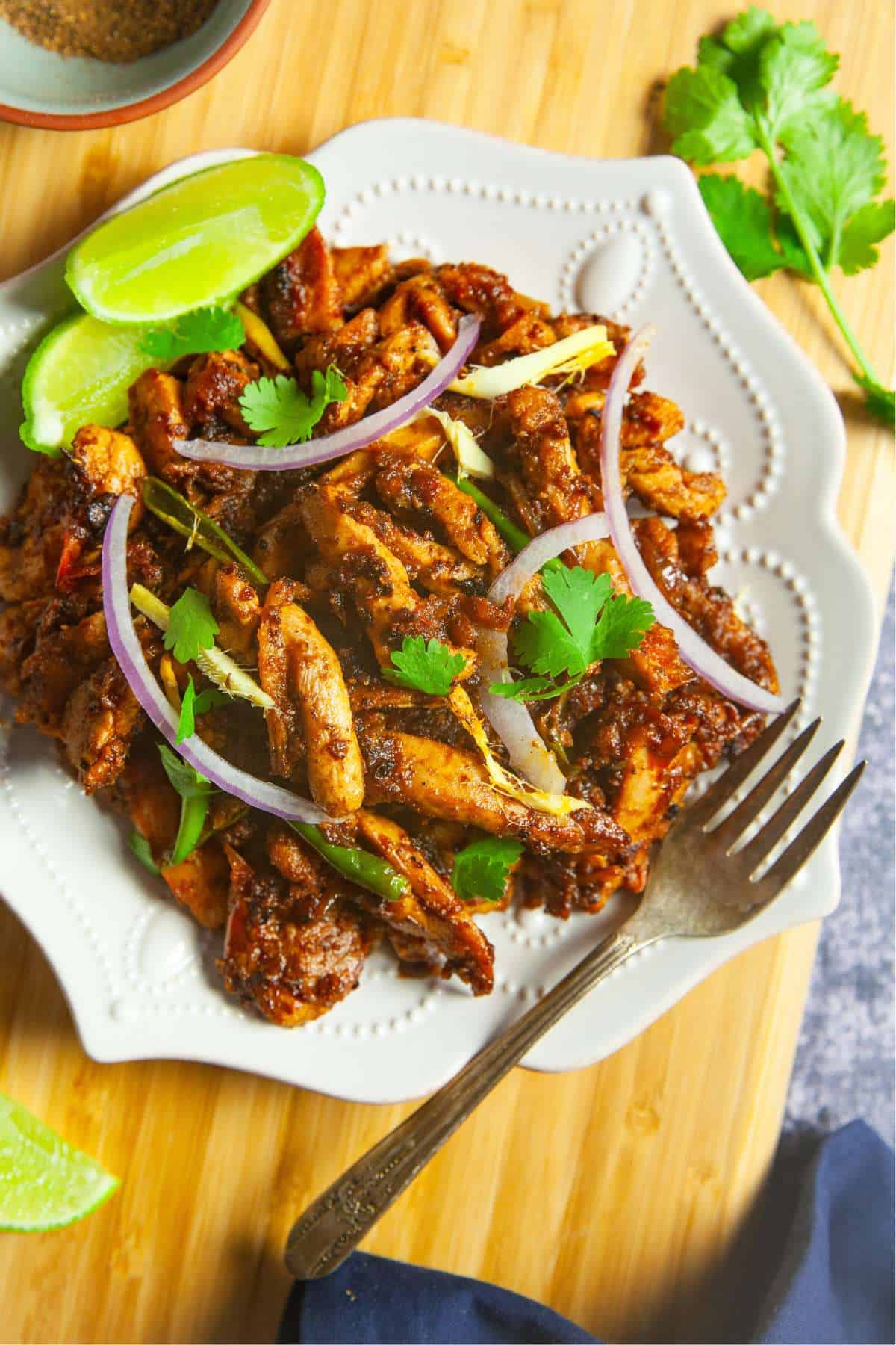 Tawa Chicken served as a indian chicken starter with lemon slices, onions and cilantro.