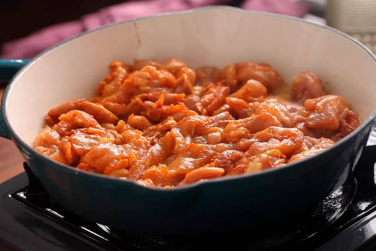 Marinated chicken is layered in hot oil in the tawa.