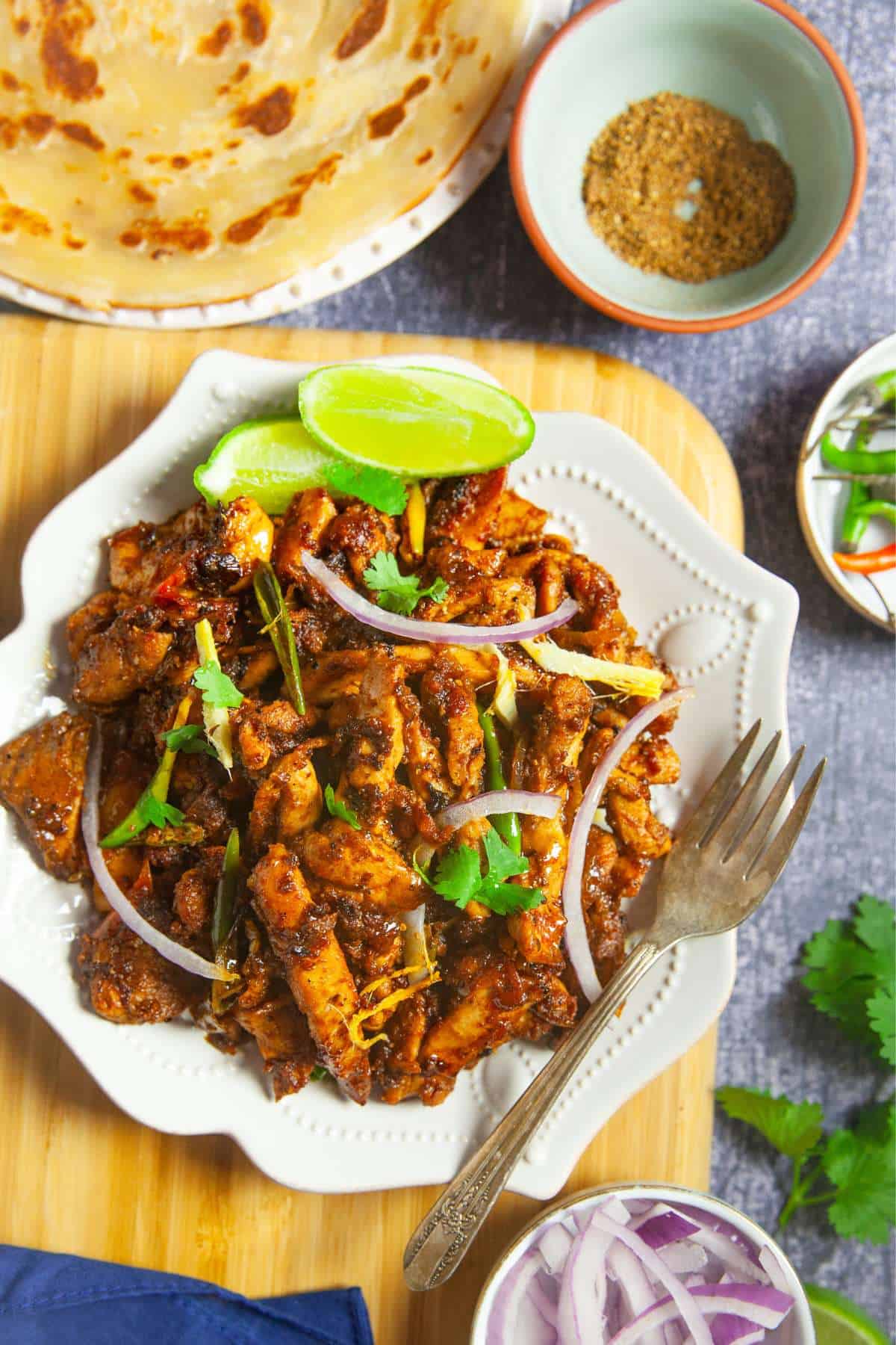 Chicken masala cooked on tawa served in a white plate.