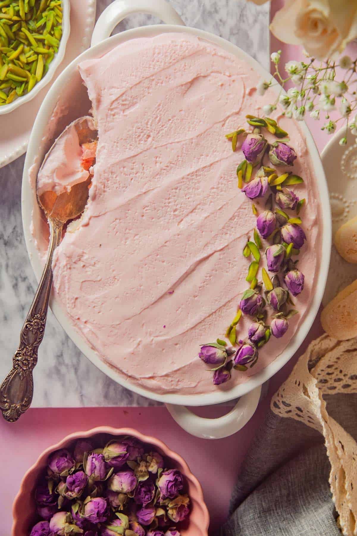A dish of rose tiramisu scooped out from side. 