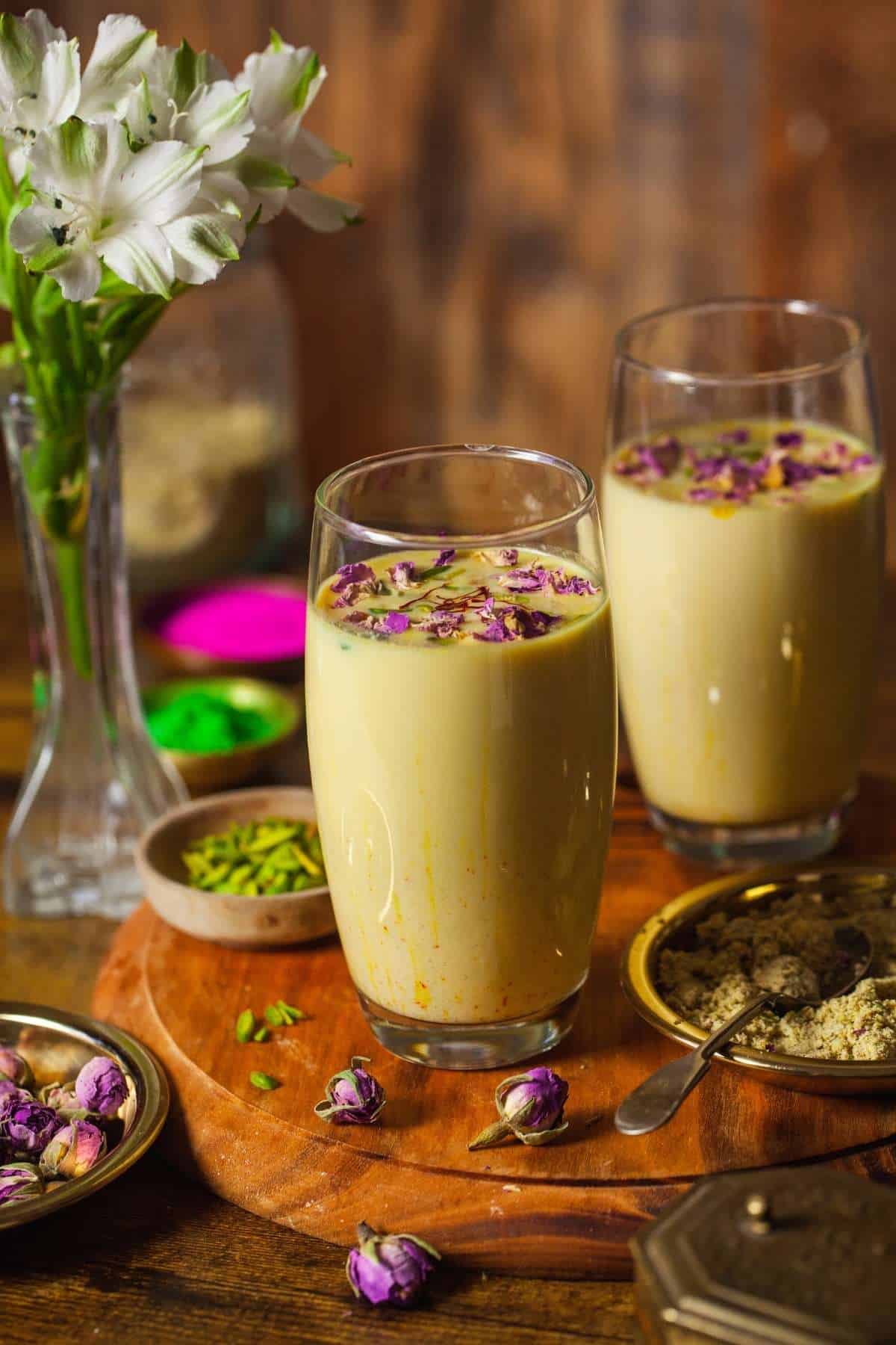 Chilled Thandai in a glass garnished with nuts, rose petals and saffron.