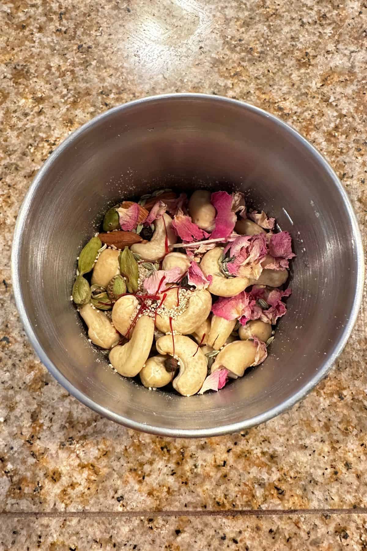 Thandai Powder ingredients in a stainless steel grinder jar. 