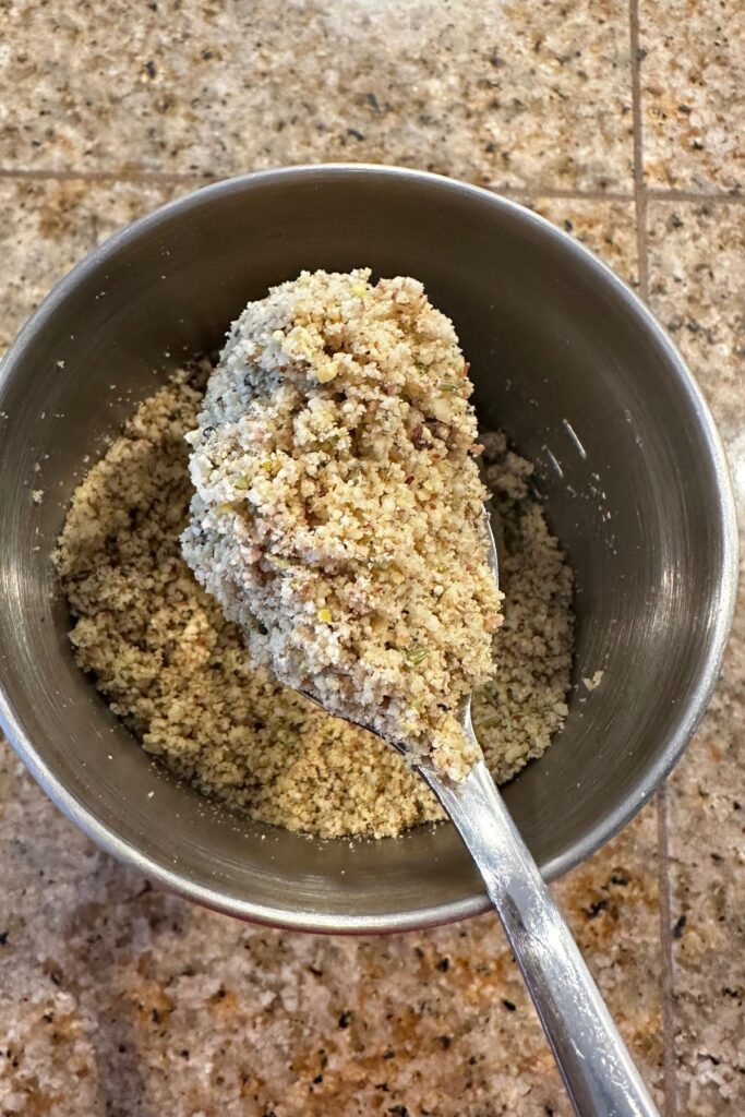 Ground thandai masala in a spoon.