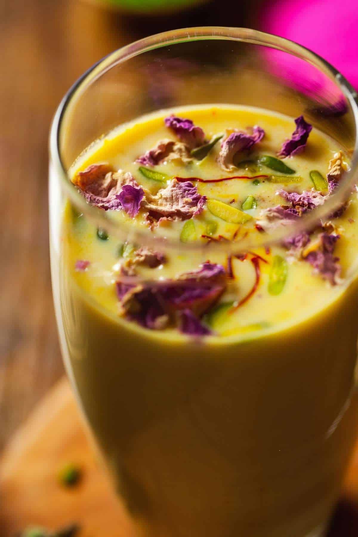 Thandai in a glass garnished with nuts, rose petals and saffron. Closeup shot