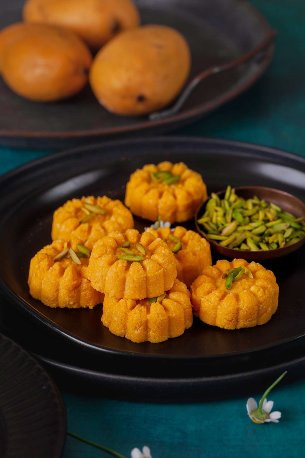 Mango Sandesh on a black platter garnished with pistachios