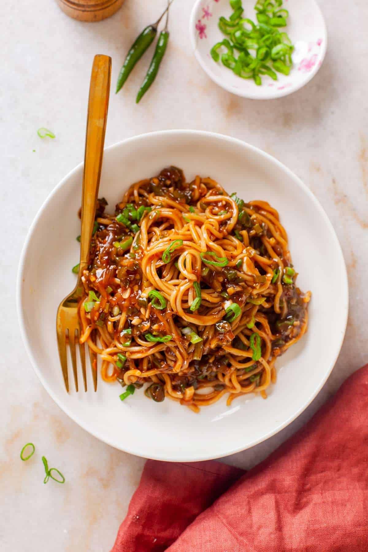 Manchurian Noodles in a white bowl With Gold Spoon
