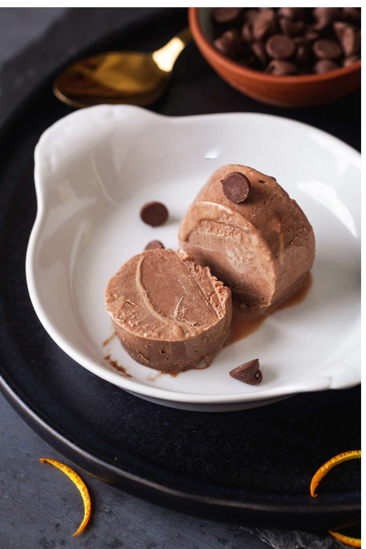 Kulfi cut on a white dish and garnished with chocolate chips. 