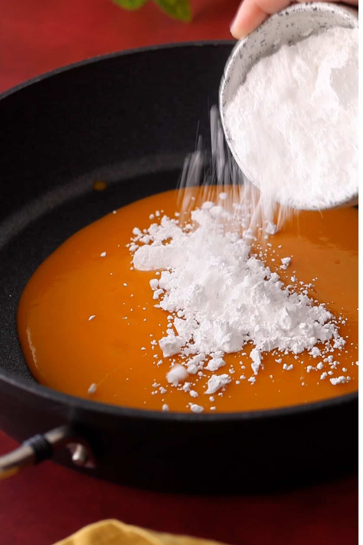 Adding mango puree and sugar in a large non stick pan.