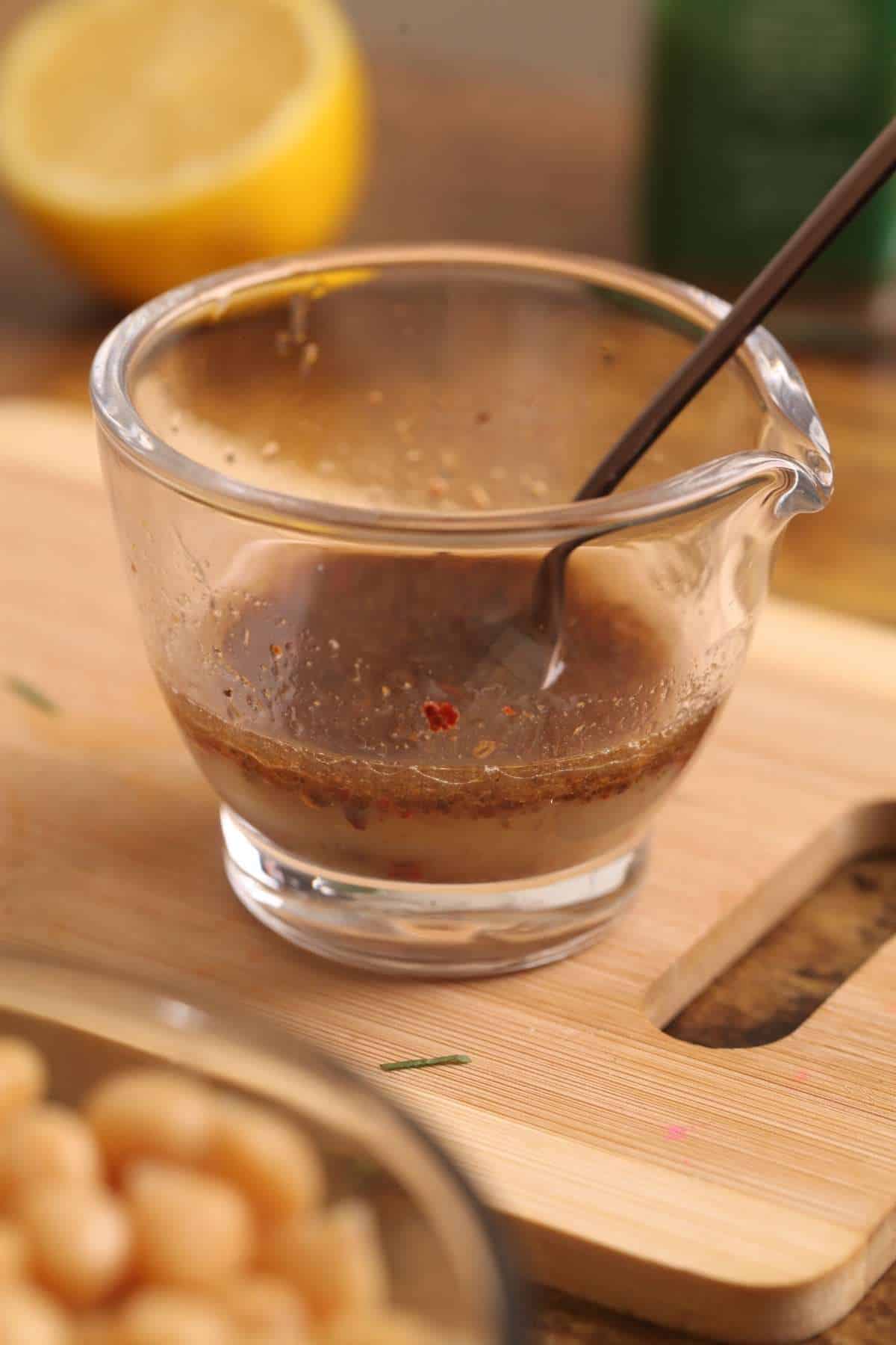 Dressing for paneer salad in a small glass bowl with spout. 