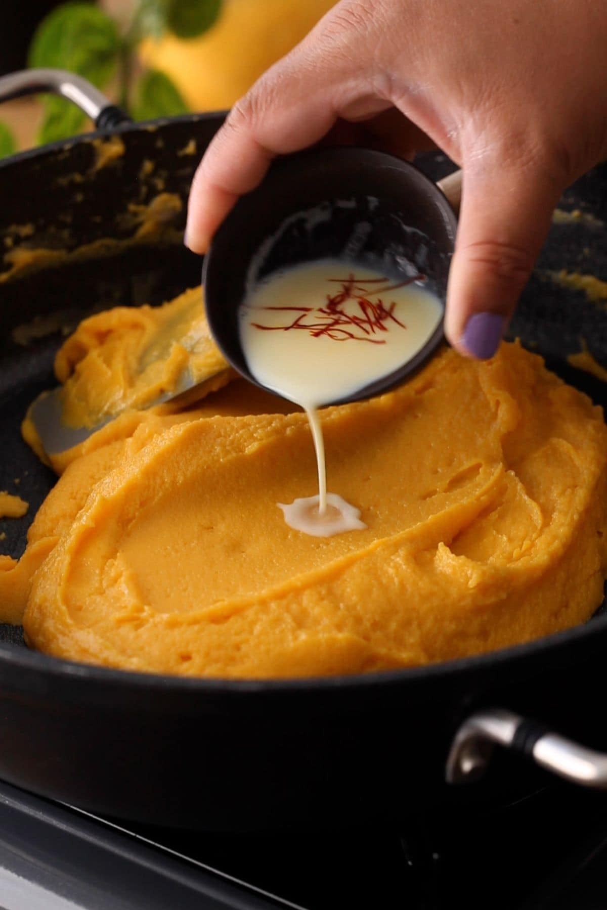 Adding saffron to the burfi mixture.