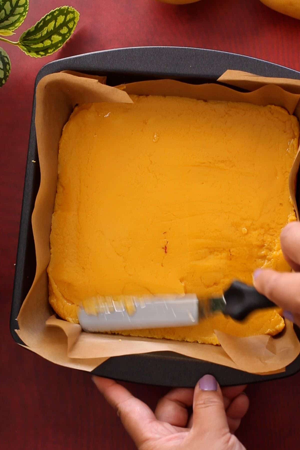 Setting mango burfi mixture in a square dish.