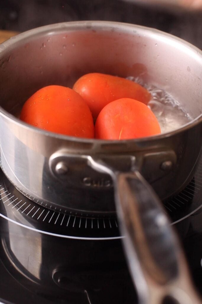 Blanch the tomatoes by adding them to boiling water.