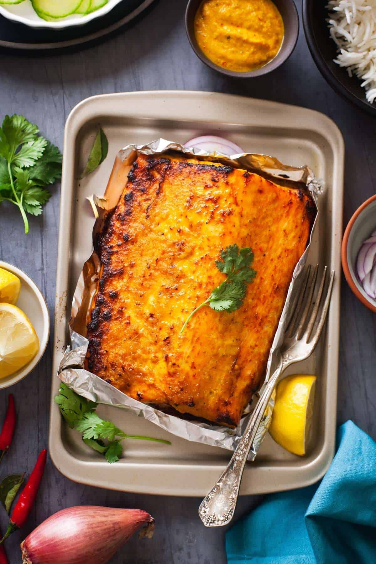 Spicy Indian Baked Salmon on a baking sheet with fork.