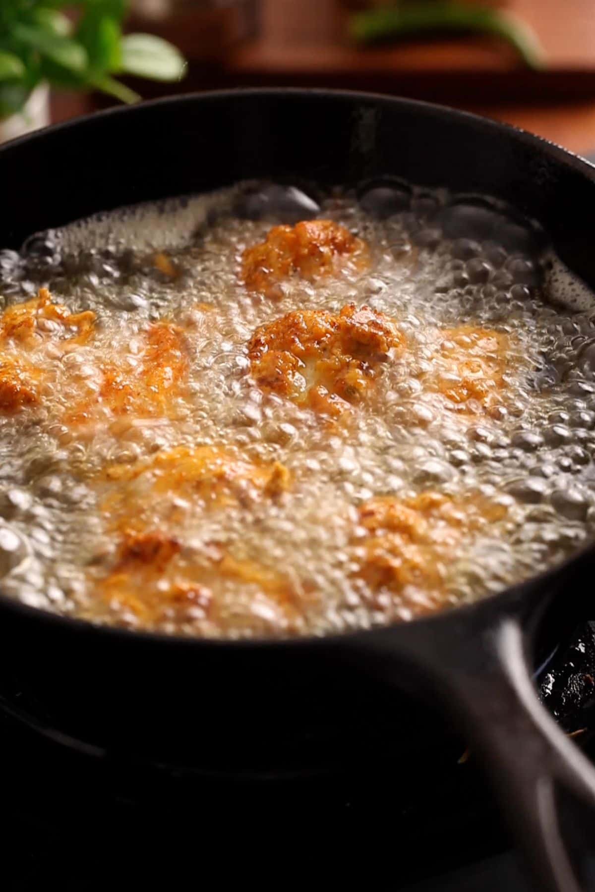 Fish is deepfrying in a cast iron skillet.