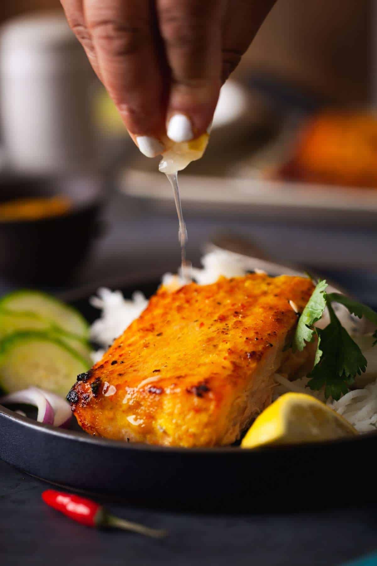 Action shot of fresh lemon squeezed on baked salmon.