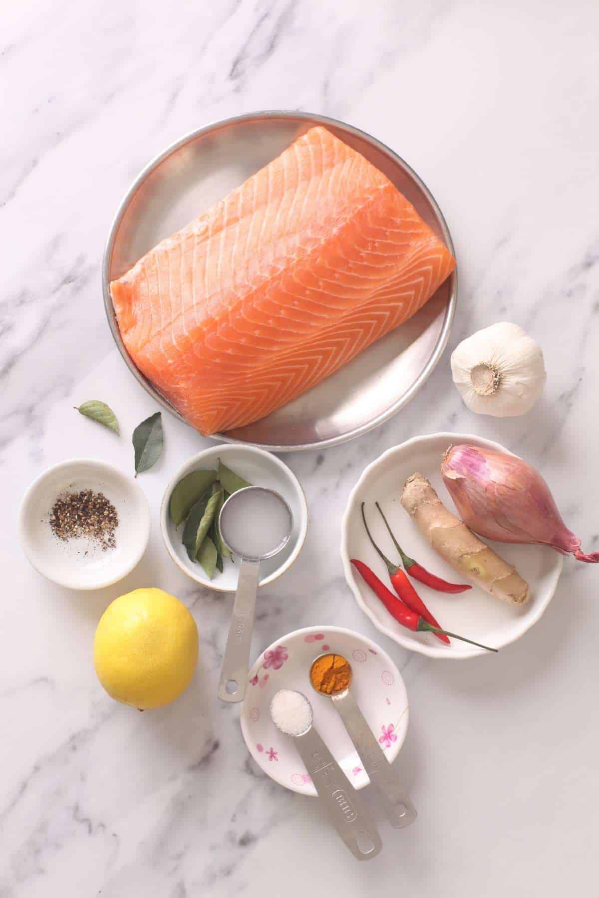 Ingredients needed to make salmon on a marble background.