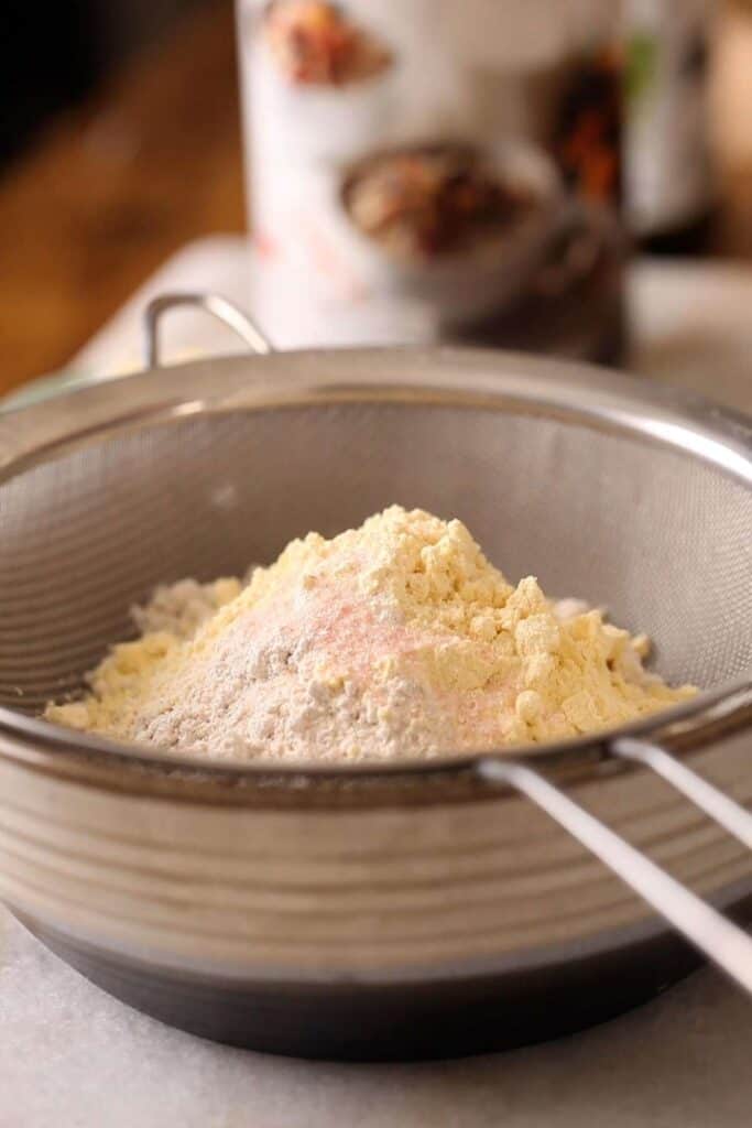 Adding flours to the colander to sieve.