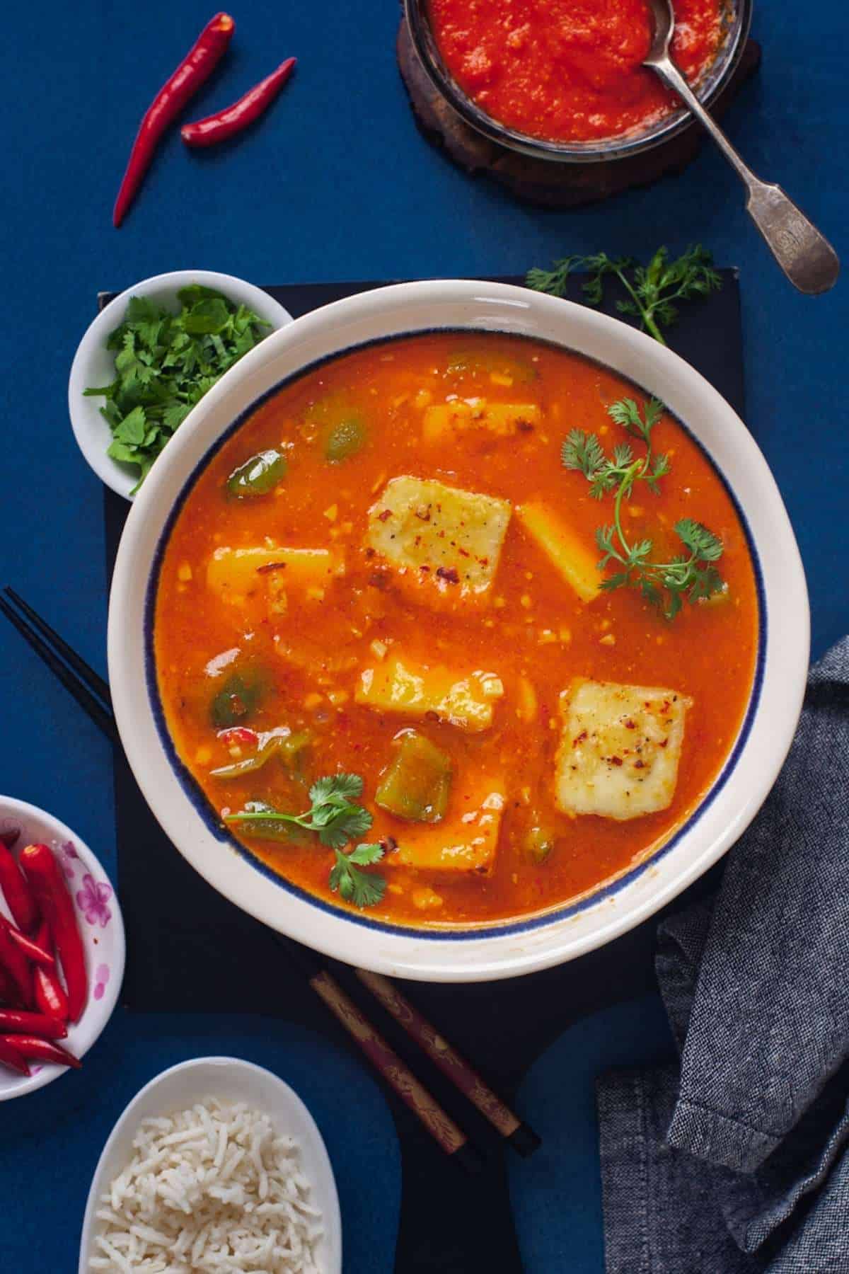 Paneer in Hot Garlic Sauce With Thai Bird Chilies and chilli garlic sauce on a blue background. 