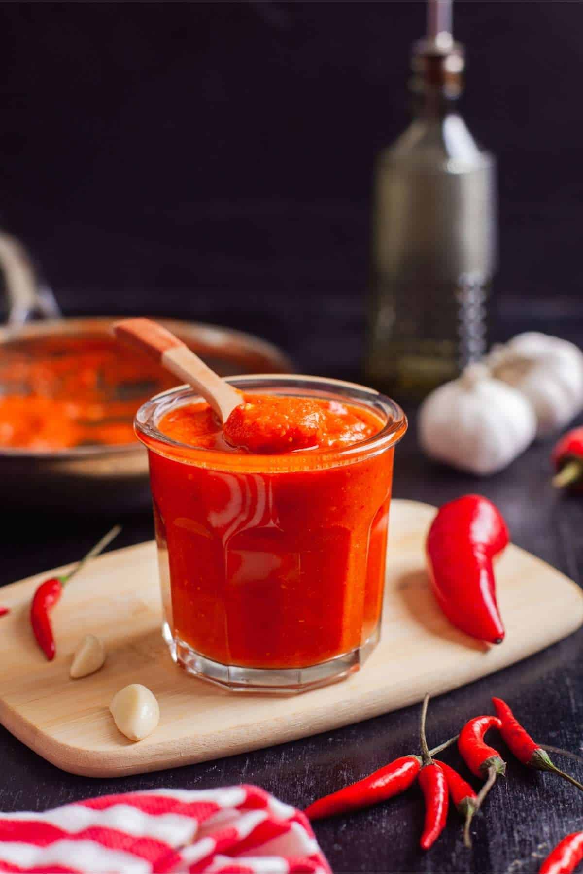 Hot Garlic Sauce in a glass mason jar with a wooden spoon.