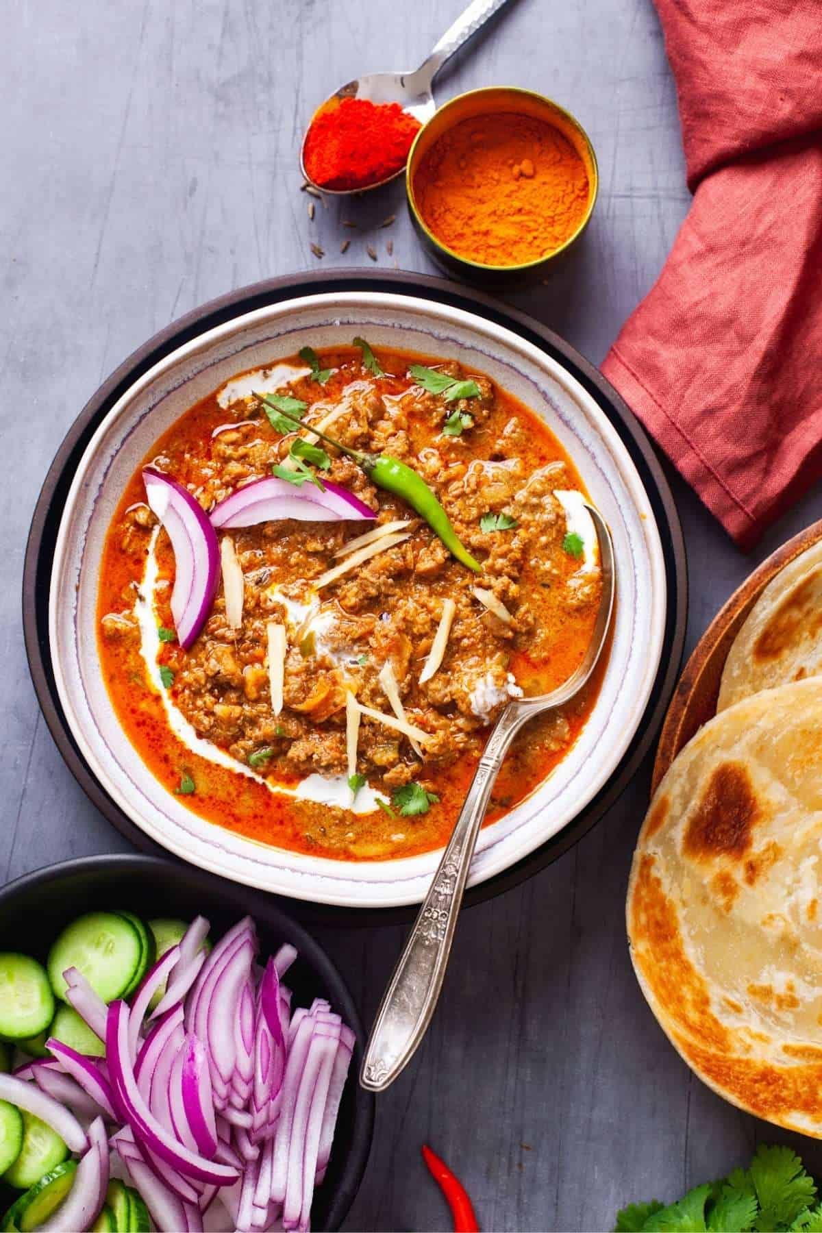 Dhaba Style Keema Masala in a bowl with salad and parathas(flatbread). 