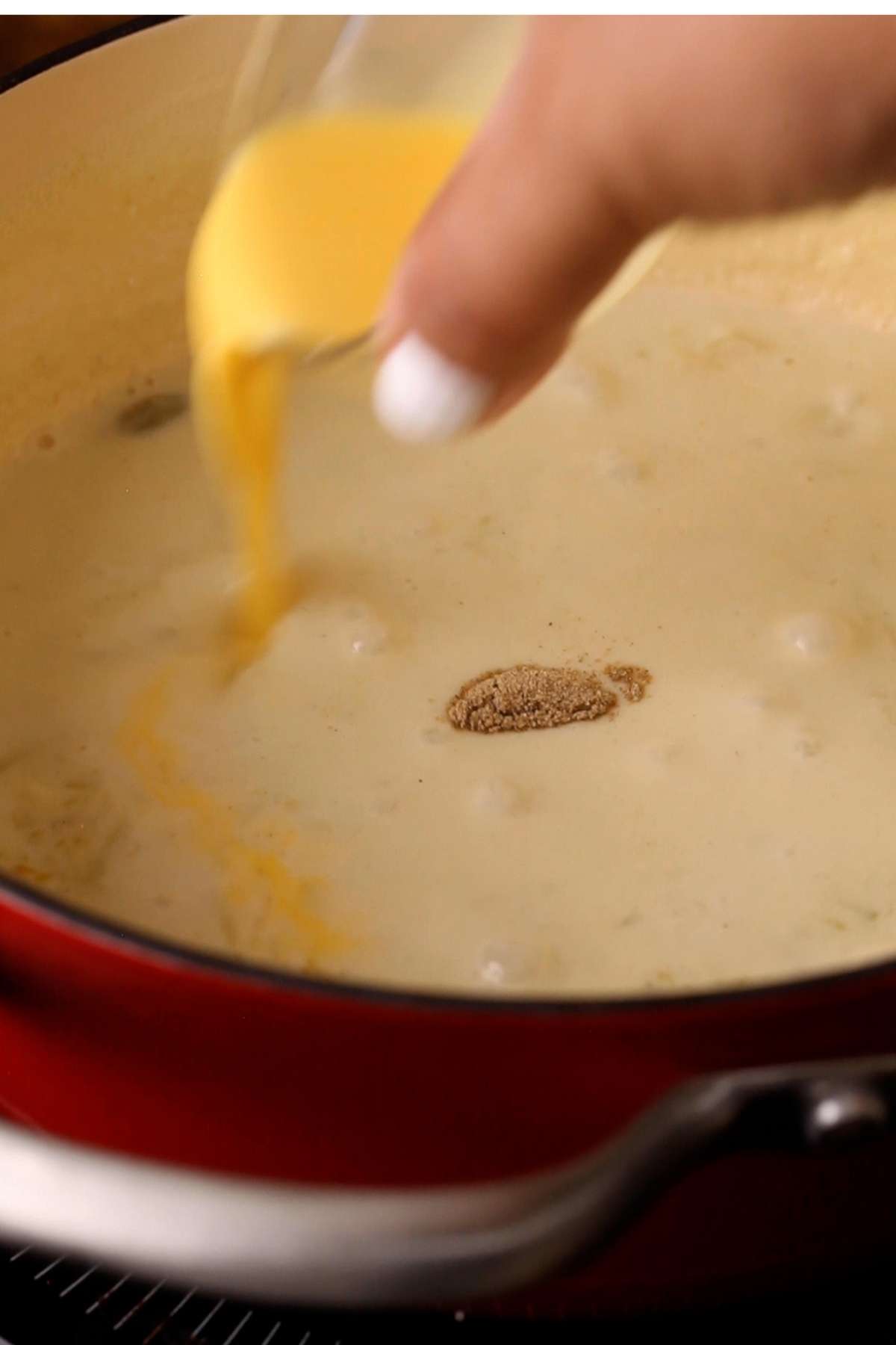 Adding custard powder to the cooked pudding.